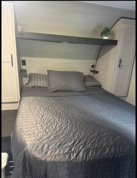 Comfortable RV rental bedroom featuring a large bed with grey bedding, overhead shelf, and side cabinets.. Sportsmen by KZ 250THLE 2022