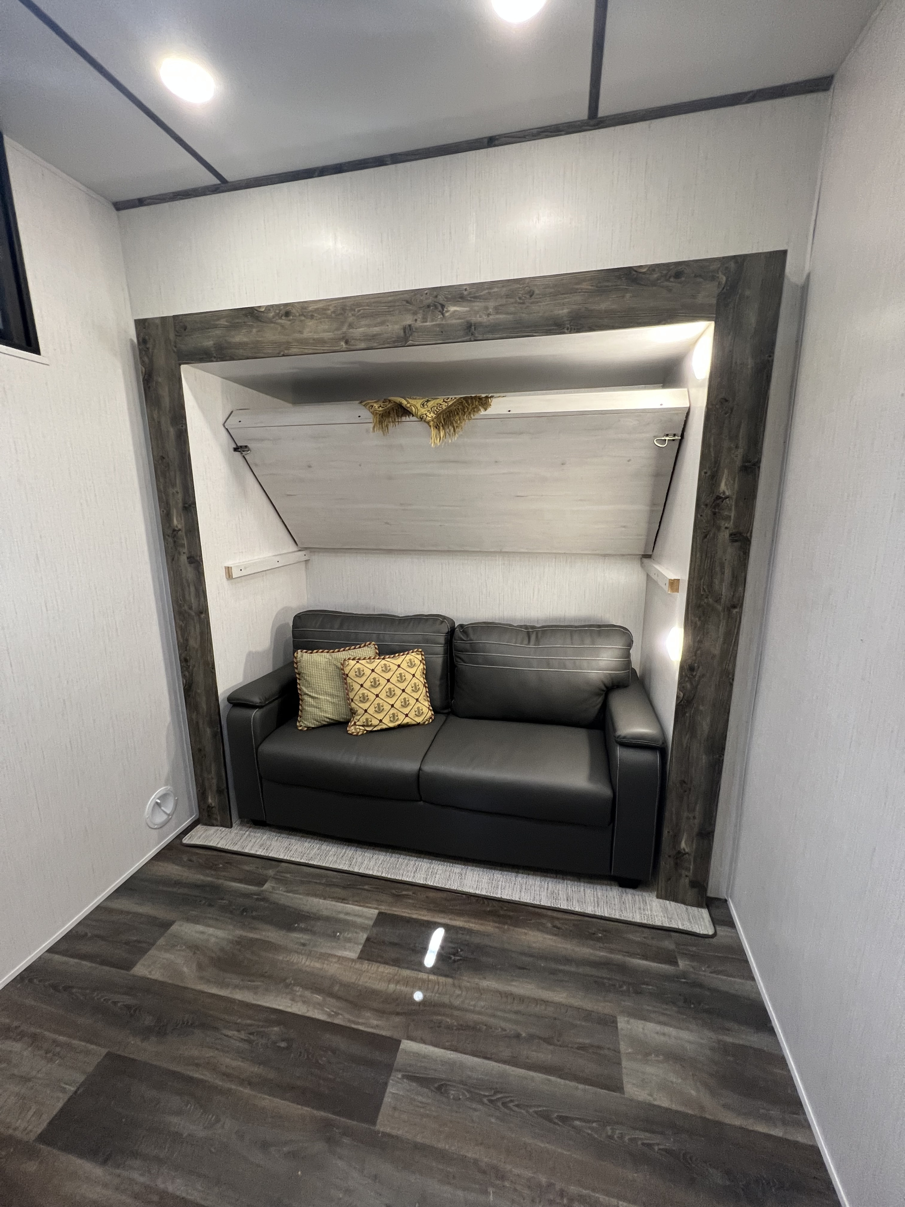 Compact and modern RV rental interior featuring a comfy sofa and a space-saving murphy bed.. Heartland Bighorn Traveler 2022