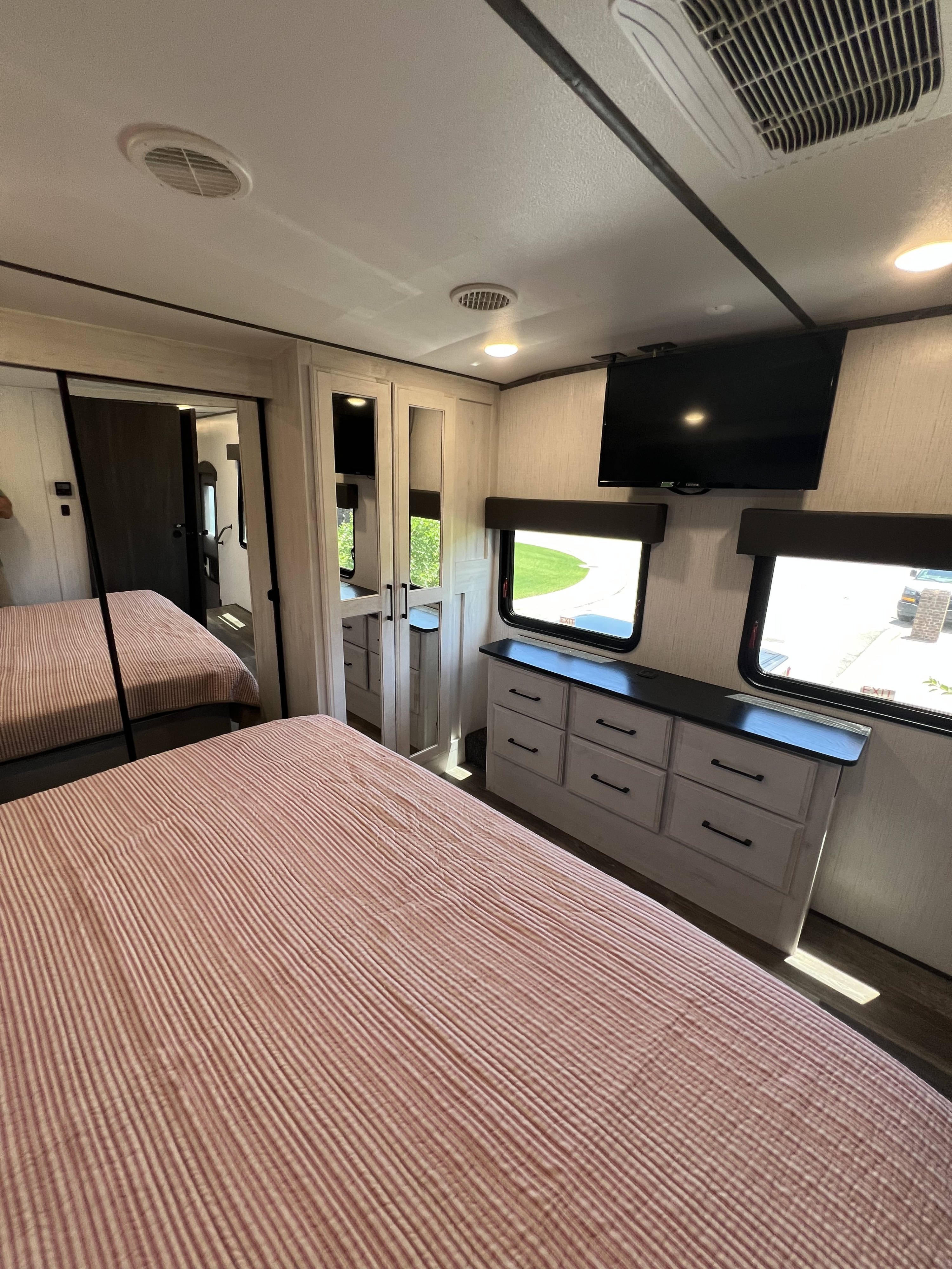 Well-appointed rv rental bedroom with two beds, dresser, windows, and TV.. Heartland Bighorn Traveler 2022