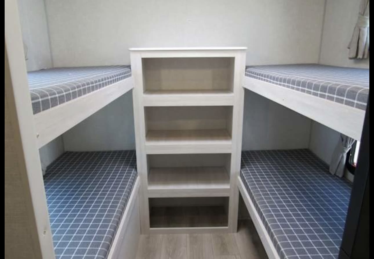 Spacious RV rental featuring comfy bunk beds and central storage shelves, ideal for family travel.. First river Surveyor 2025