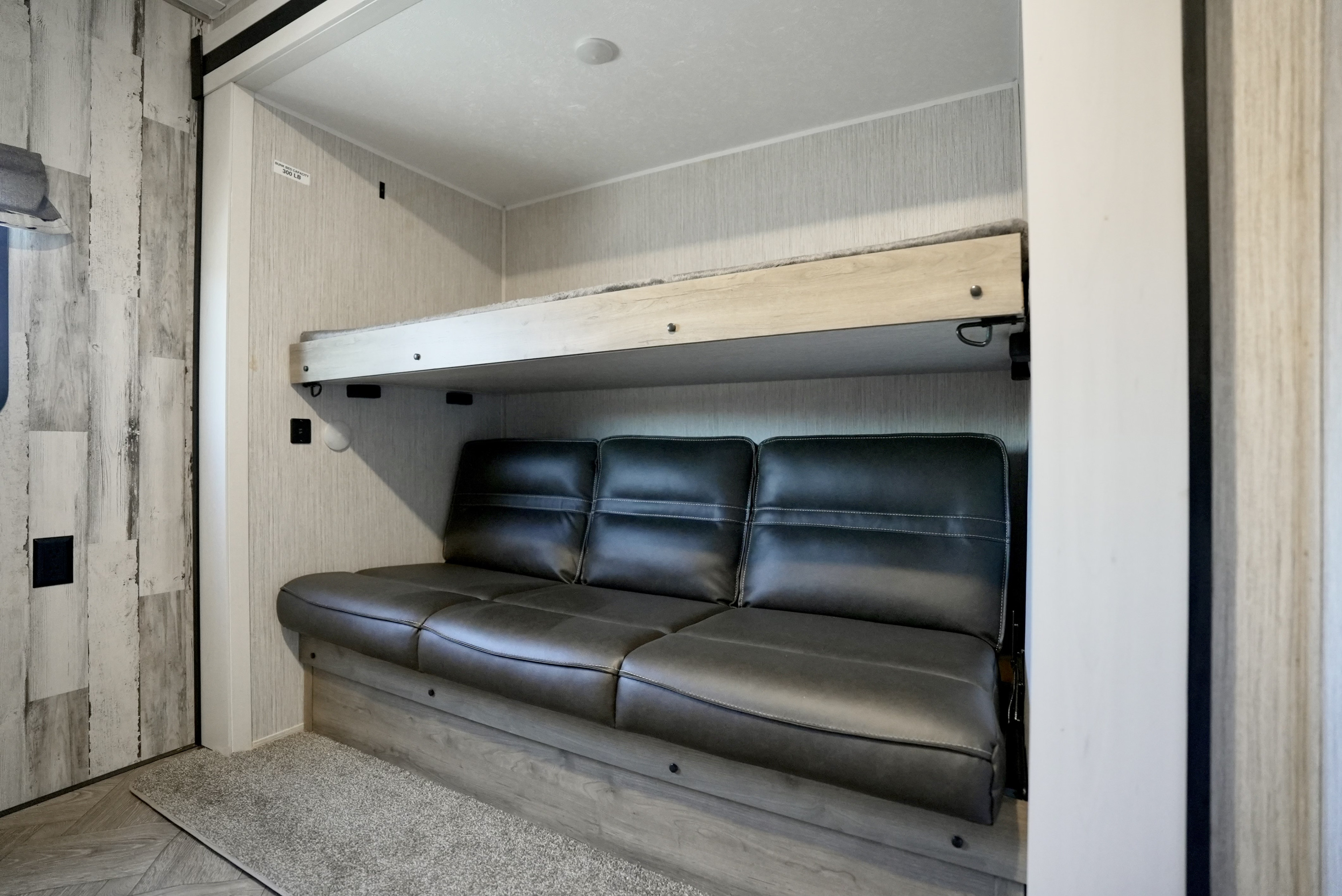 Compact RV rental interior featuring a versatile sofa below a sturdy bunk bed, maximizing living space.. Forest River Palomino Puma 2022