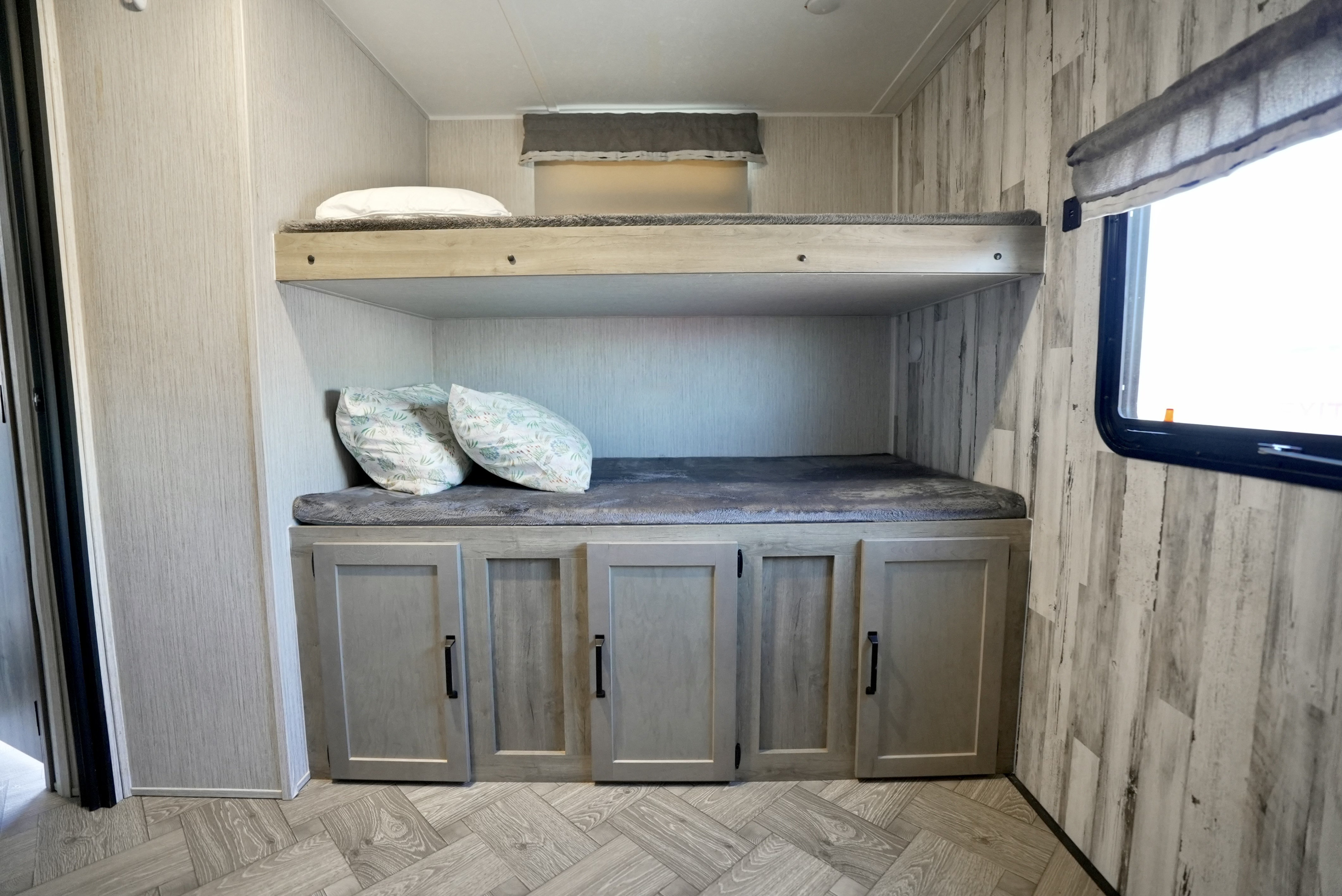Modern RV rental interior featuring two bunk beds, lower storage cabinets, and a window.. Forest River Palomino Puma 2022