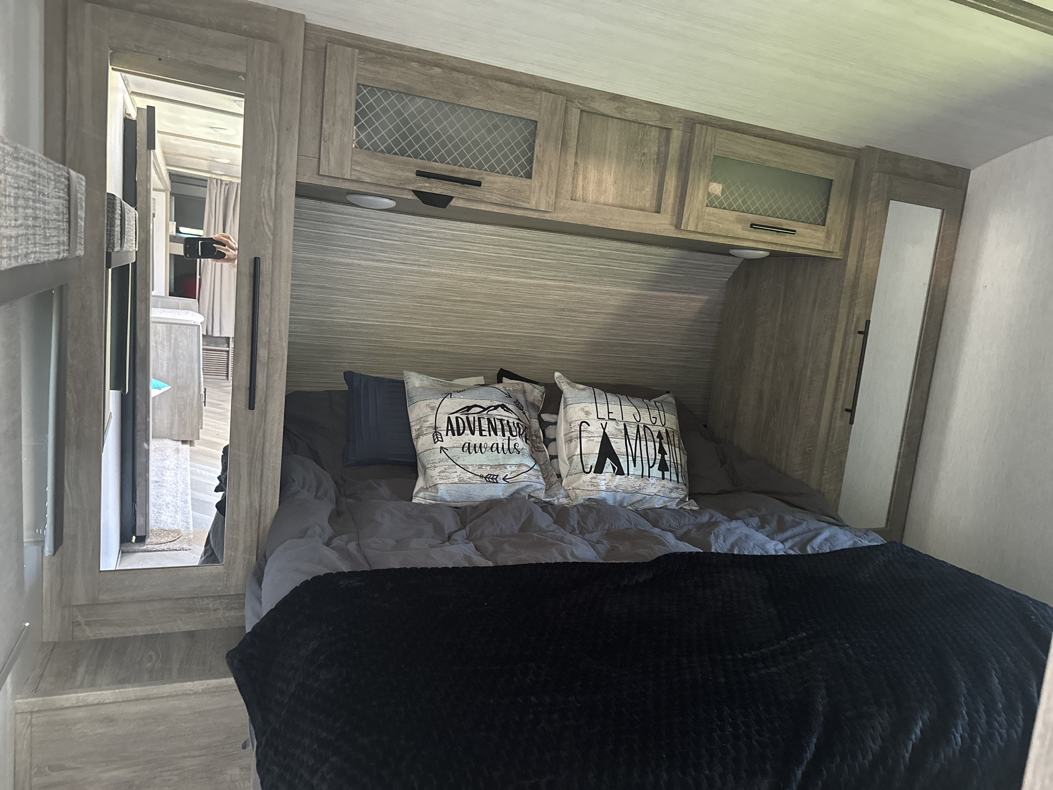 Explore a comfortable RV rental bedroom interior, featuring a cozy bed, overhead cabinets, and reflection of the RV's hallway.. Forest River Salem Hemisphere HL 2022