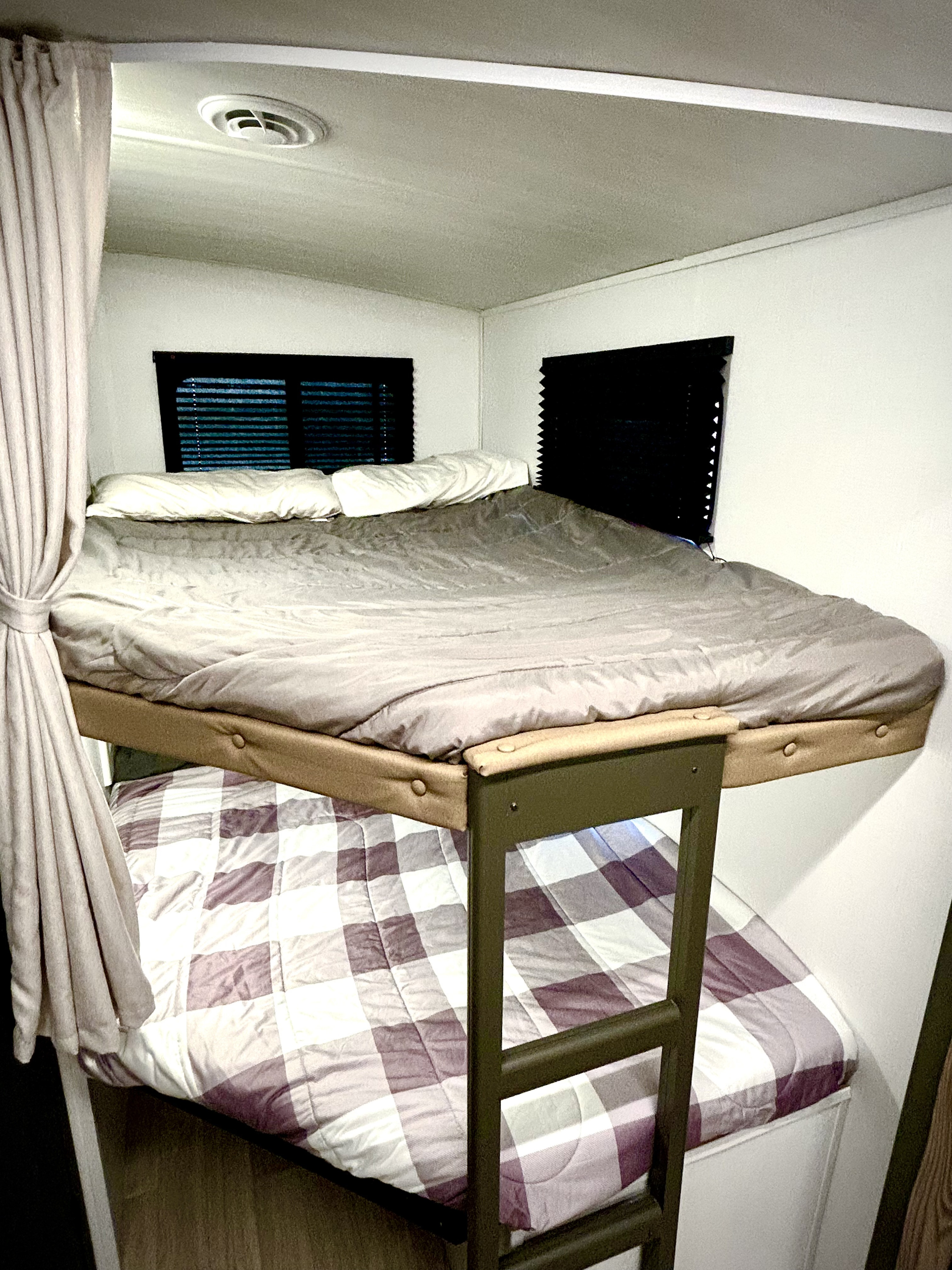 Inside an RV rental, comfortable bunk beds with plaid and grey bedding. Features small windows with blinds and a ceiling vent.. Keystone Rv 290BHSWE 2025