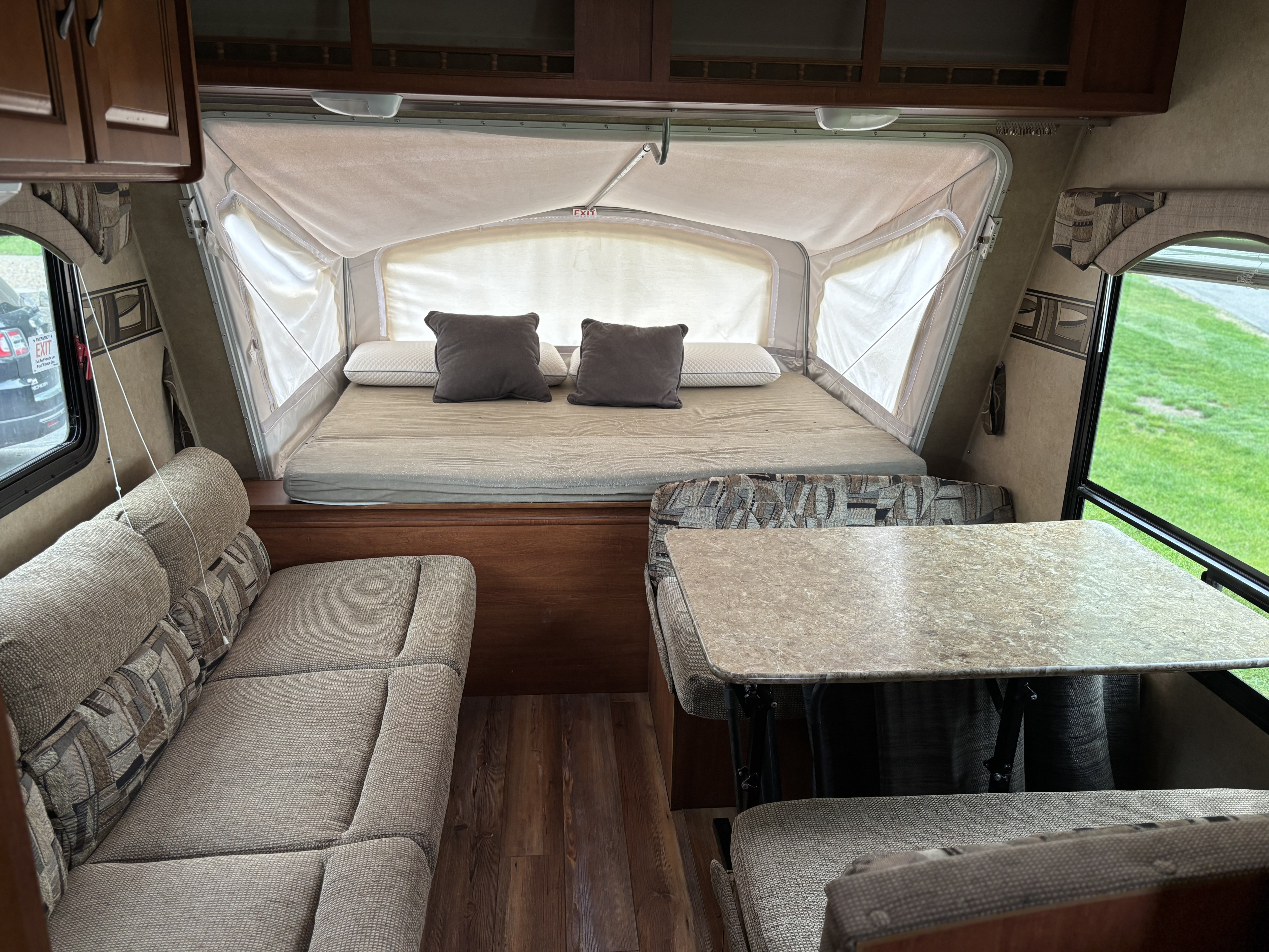 Inside a comfortable RV rental: pop-out bed with pillows, sofa, and dinette area with table. Ideal for travel.. Forest River Surveyor Sport 2011