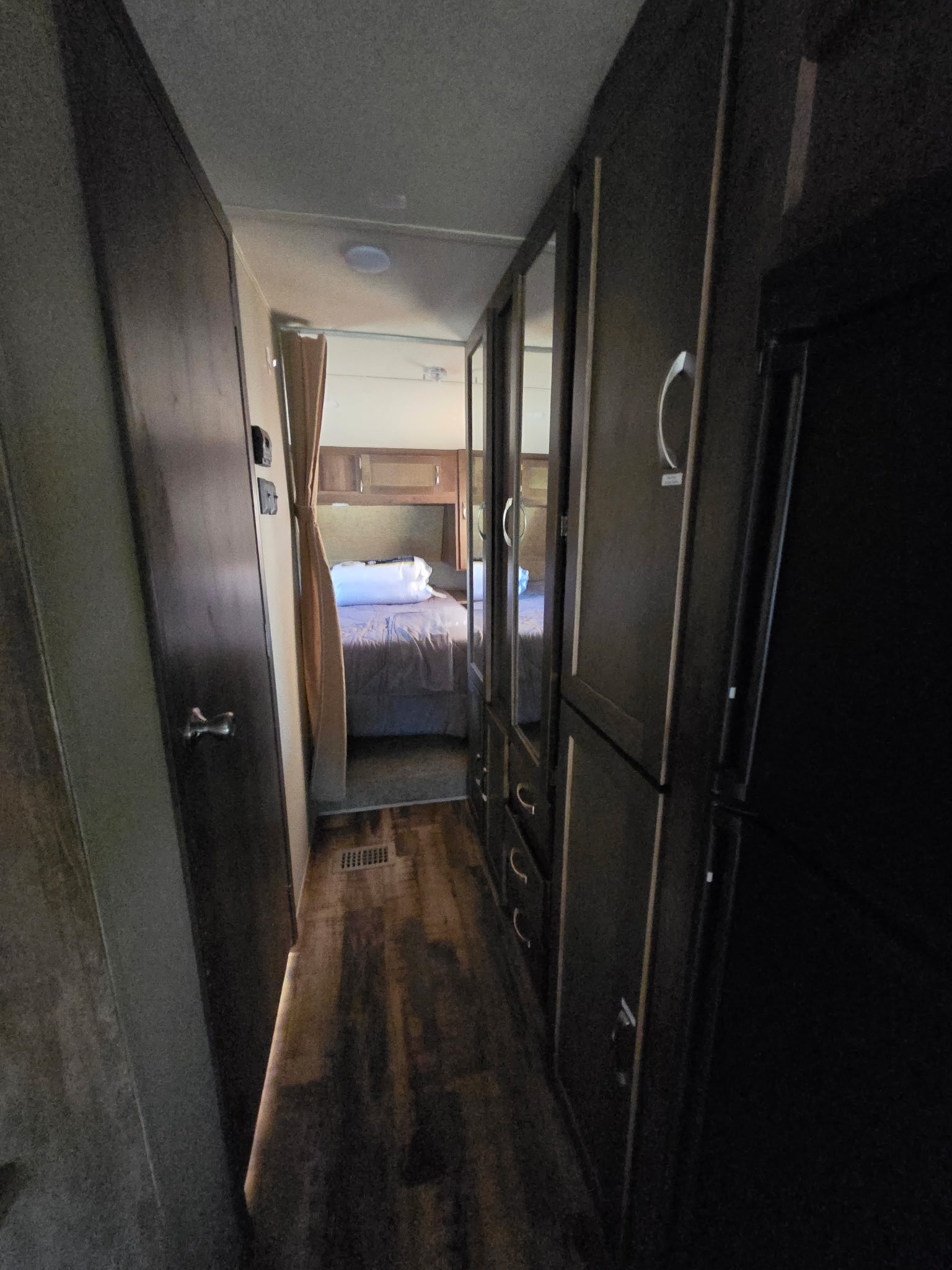 RV rental interior: A hallway leads to a cozy bedroom, flanked by dark cabinets and a fridge on the right.. Forest River Palomino Puma 2017