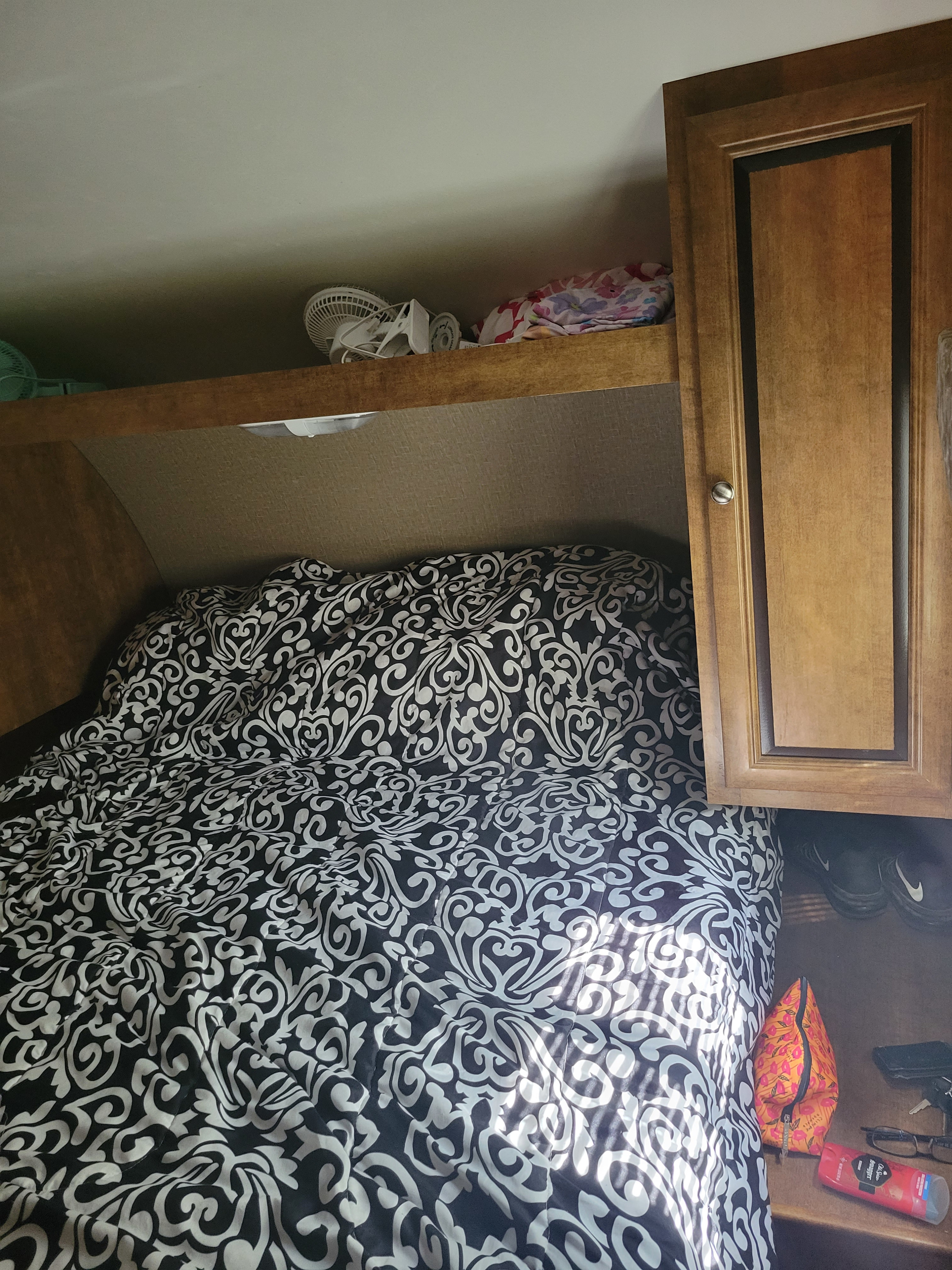 RV rental bedroom: black & white patterned bed, overhead shelf with fans, and wooden cabinet storage.. Crossroads RV Z-1 2016