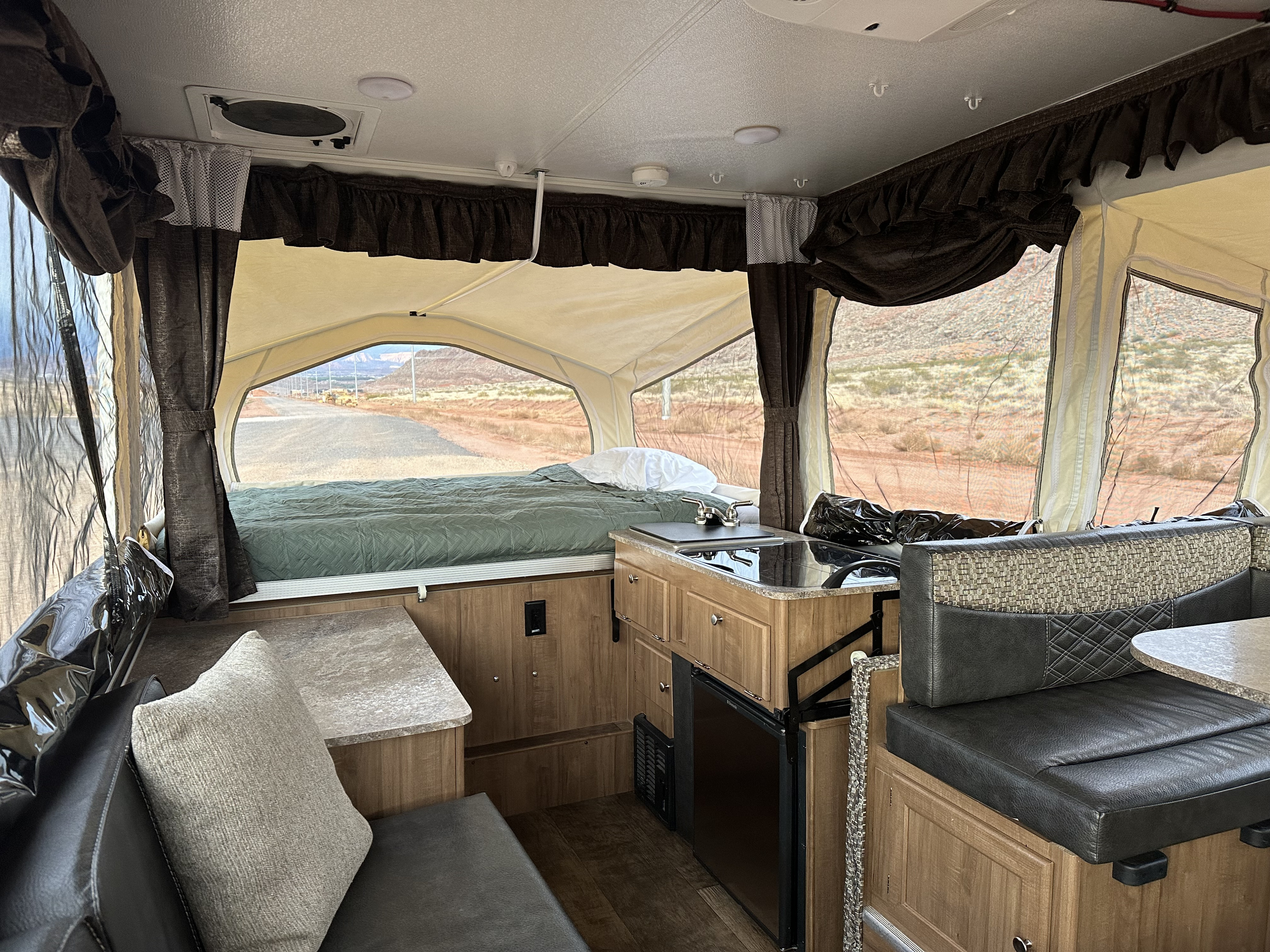 Interior of an RV rental pop-up camper, featuring a bed, kitchenette, dinette, and scenic outdoor views.. Forest River Rockwood Premier 2017