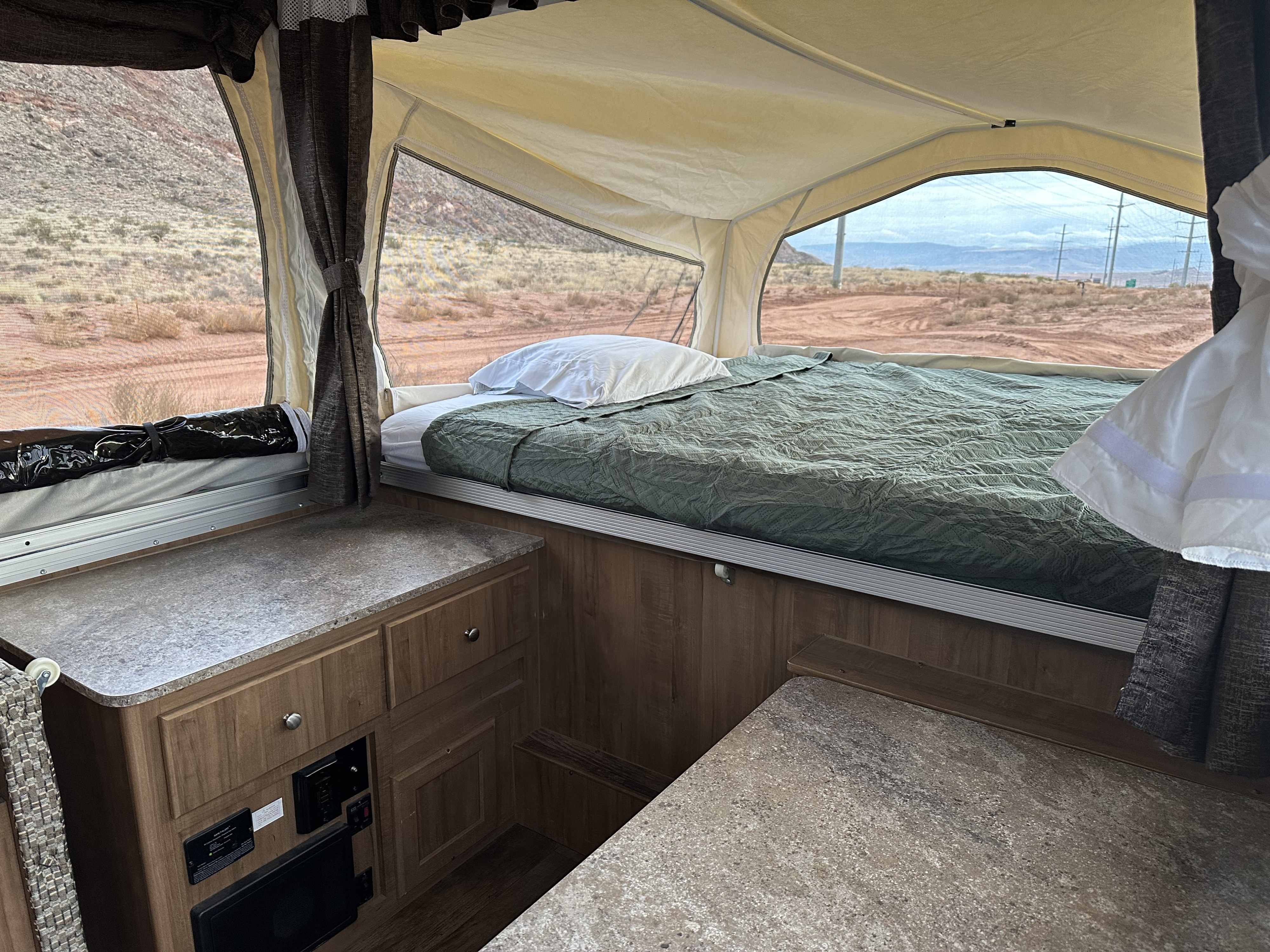 Inside an RV rental pop-up camper: a comfy bed with desert views.. Forest River Rockwood Premier 2017