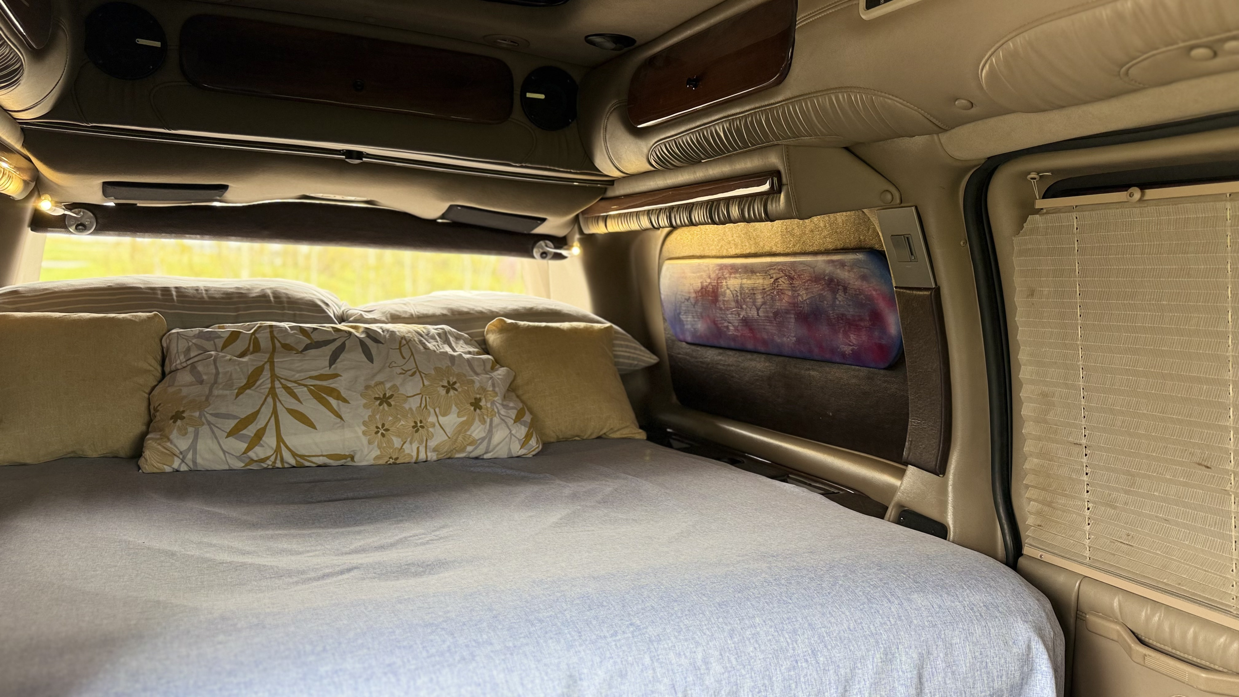 Explore a comfortable RV rental interior: a soft bed, overhead compartments, and window privacy blinds.. Gmc Custom Savana 2007