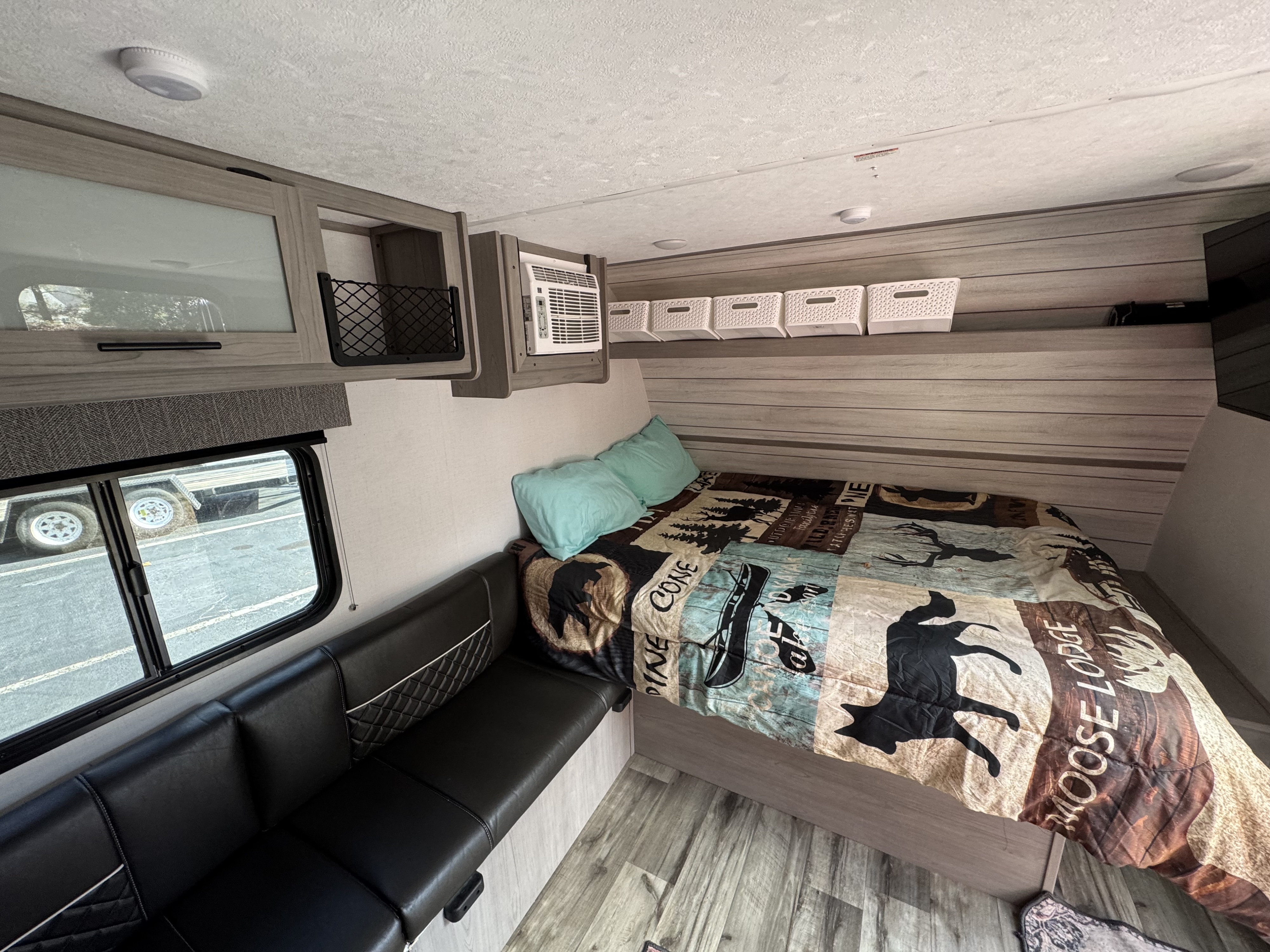 Cozy RV rental interior featuring a bed, dinette, overhead storage, and window view, ideal for travel.. Keystone RV Coleman Lantern 17B 2024