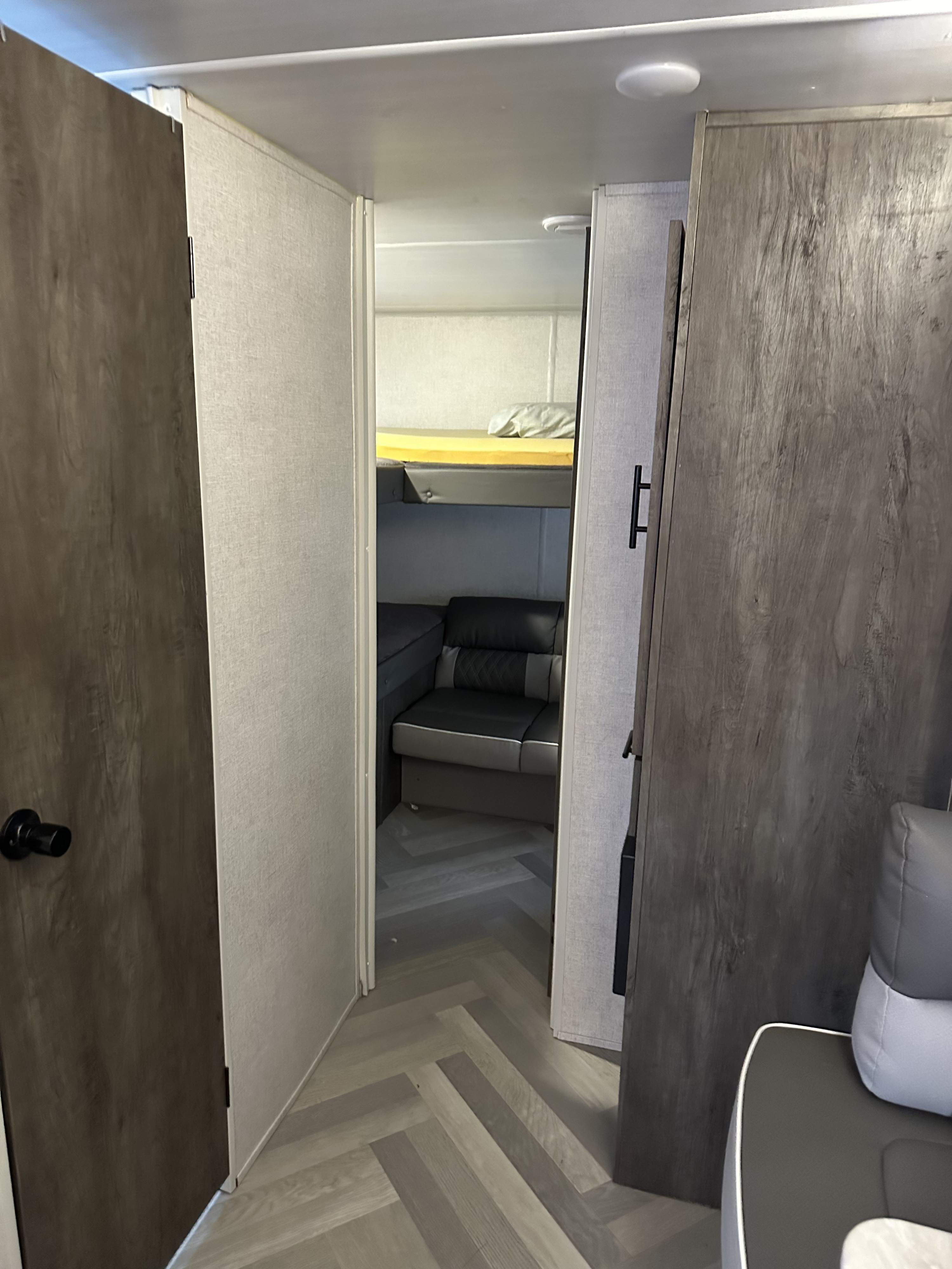 Hallway view into an RV rental bunk room, featuring upholstered dinette seating and modern wood-look floor.. Forest River Salem Cruise Lite 2022