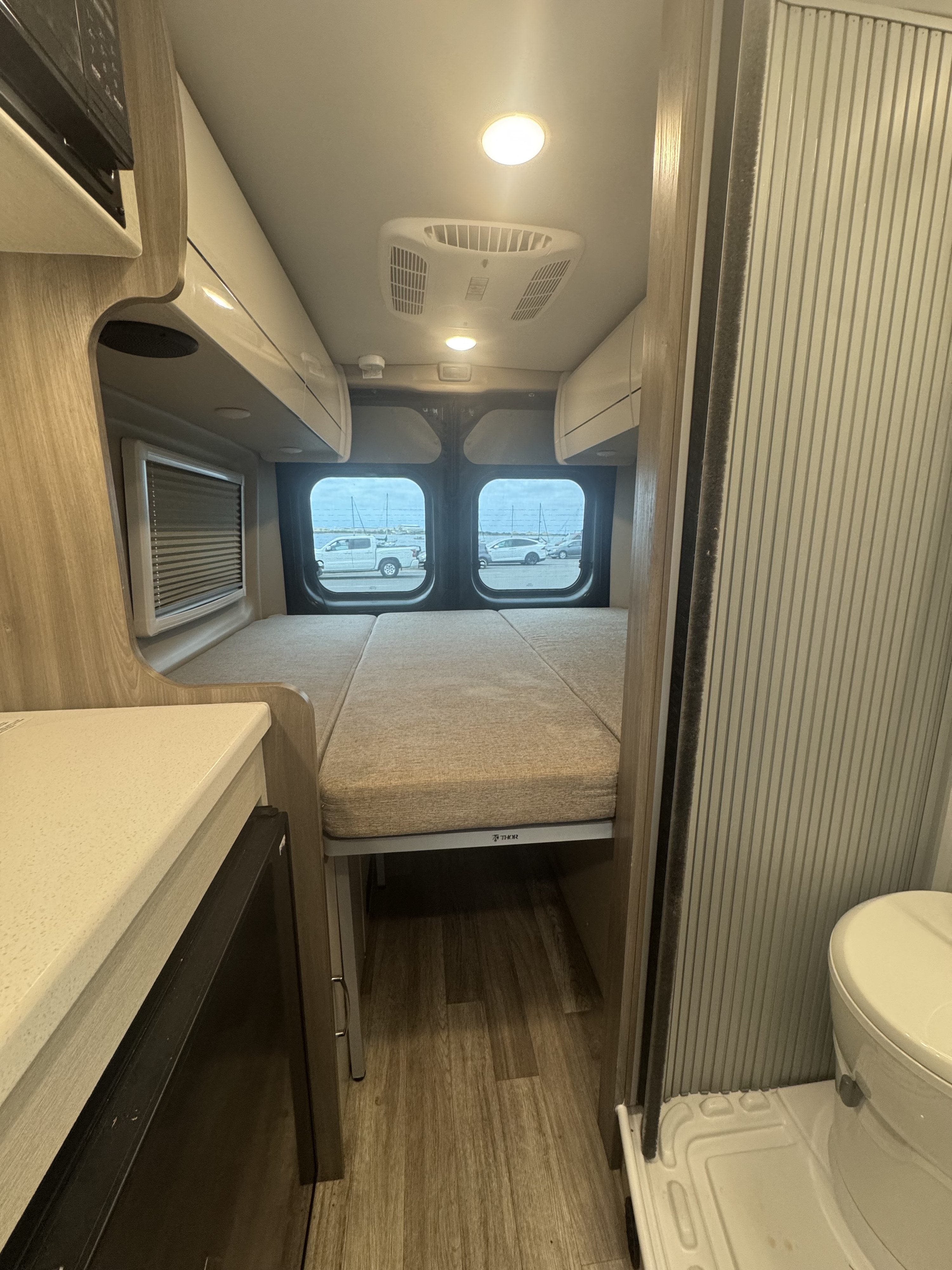 Cozy Thor RV rental interior with convertible bed, compact kitchen, and bathroom. Ideal for mobile living.. Thor Tellero 2025