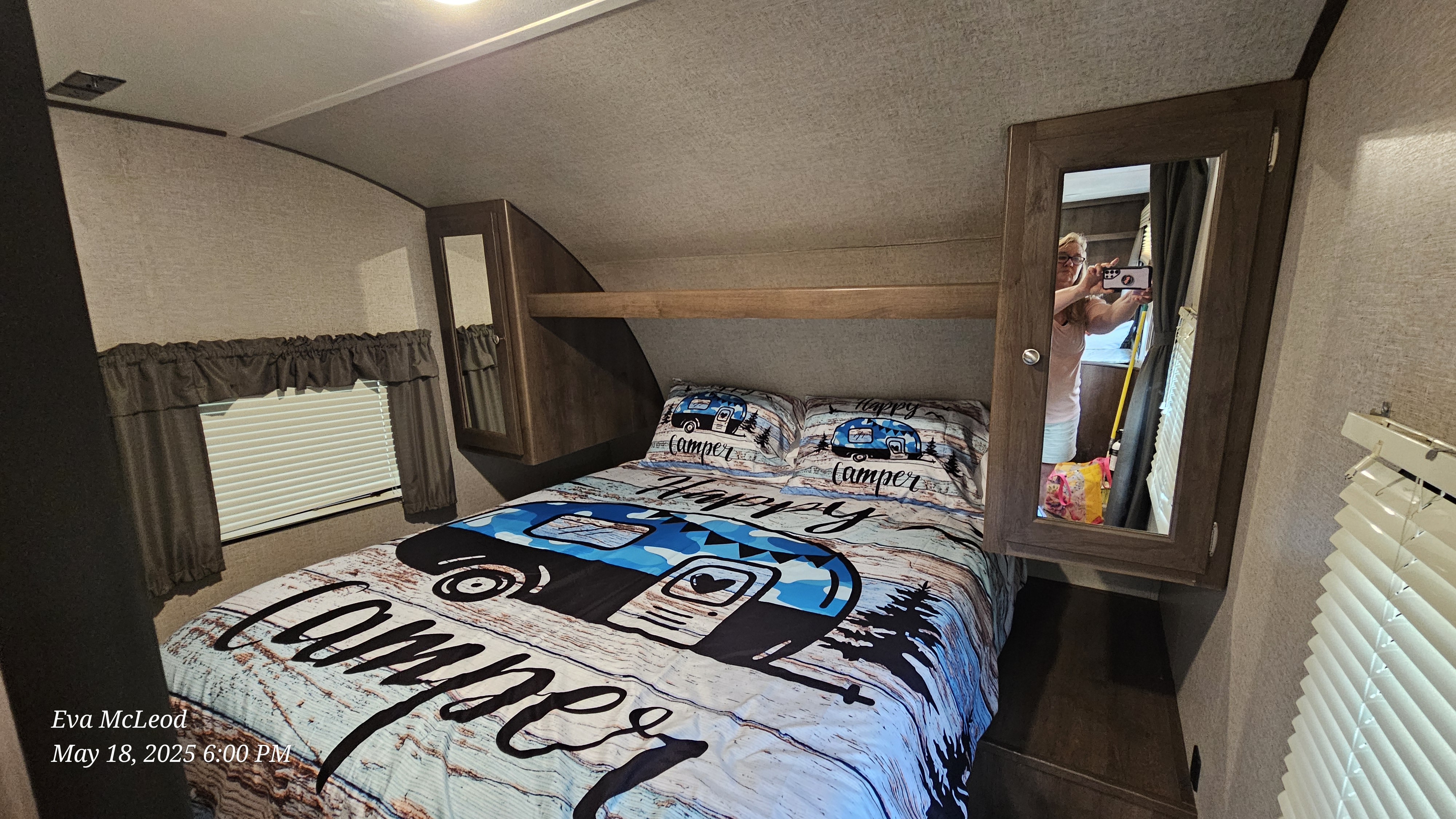 Cozy RV rental bedroom interior, featuring a "Happy Camper" bed, overhead cabinets, and window with blinds.. Forest River Shasta Oasis 2018