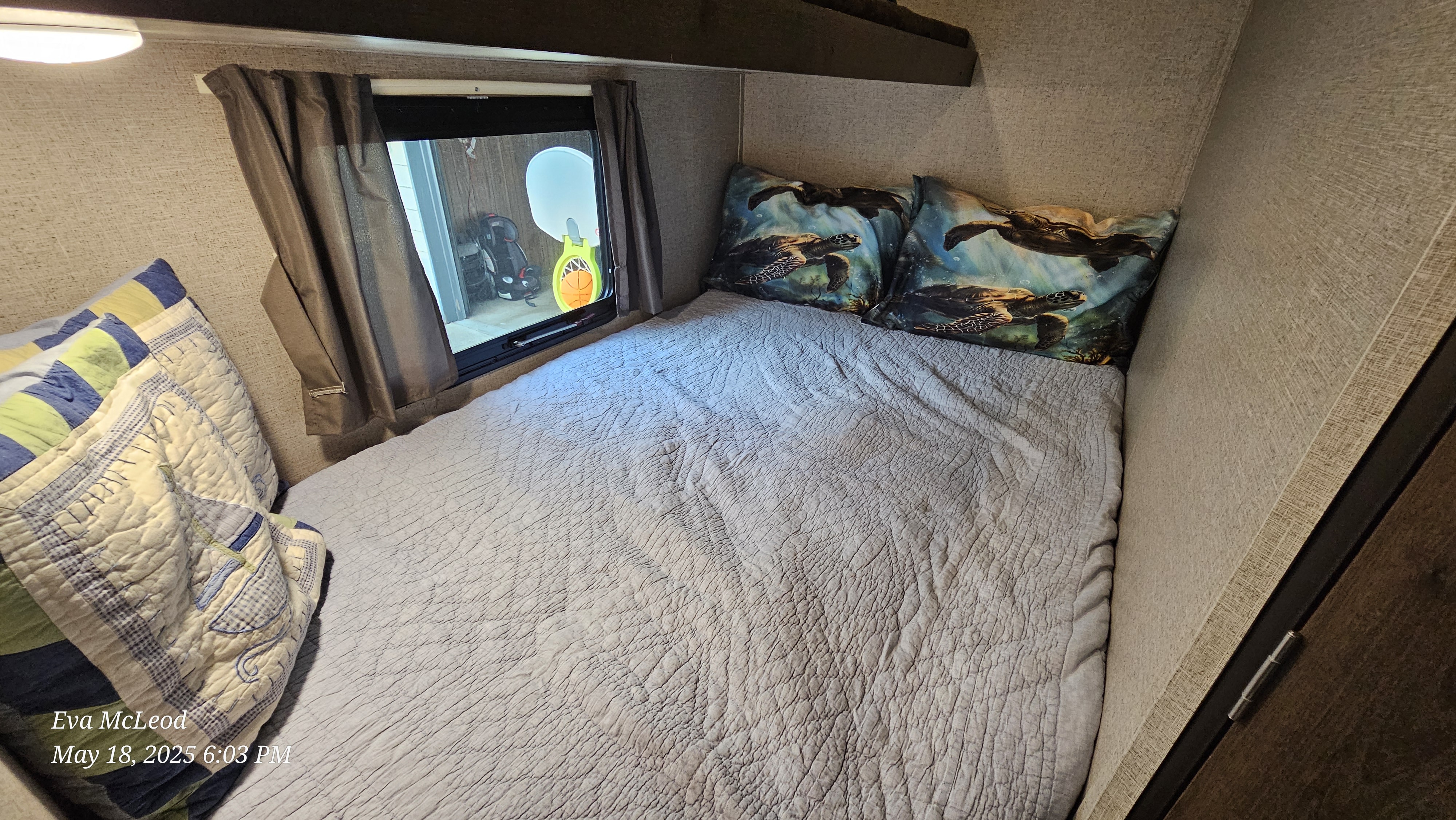 Cozy RV rental bedroom features a bed with quilted comforter, sea turtle pillows, and a window view.. Forest River Shasta Oasis 2018