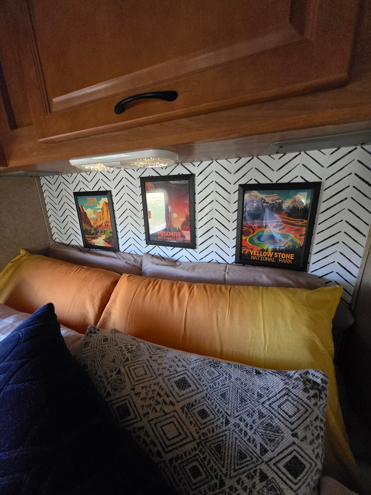 Cozy RV rental bedroom features national park art, chevron wallpaper, and vibrant pillows for a stylish travel experience.. Thor Majestic 2015