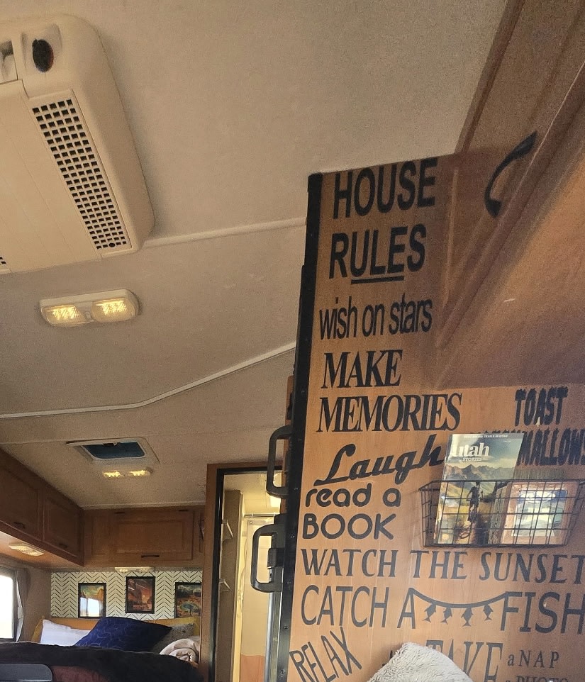 Cozy RV rental interior with a "House Rules" sign, including "Make Memories" & "Read a Book," plus a bedroom area.. Thor Majestic 2015