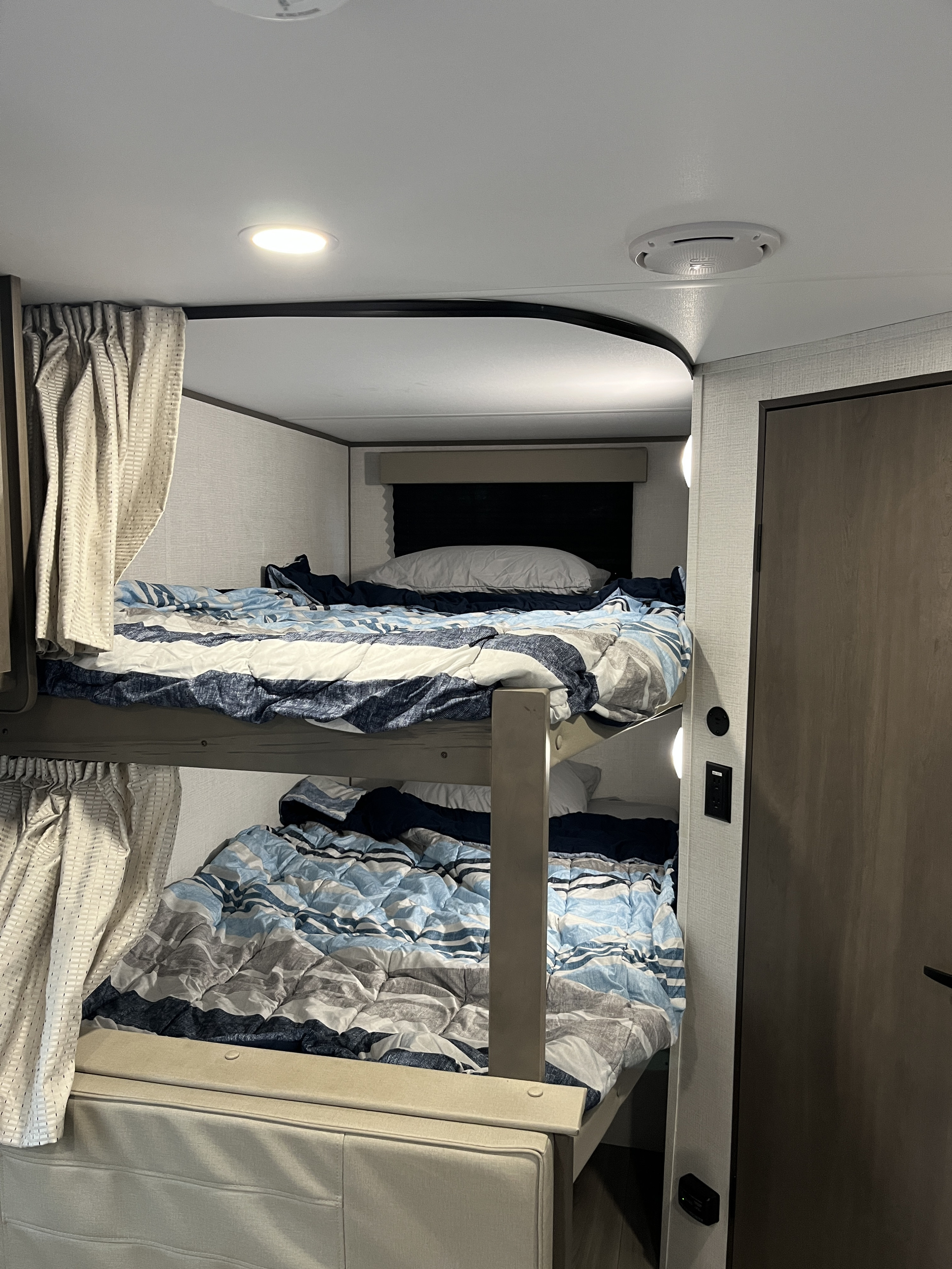 Inside an RV rental: cozy bunk beds with striped bedding and privacy curtains, ideal for family adventures.. Grand Design 26BHX 2025