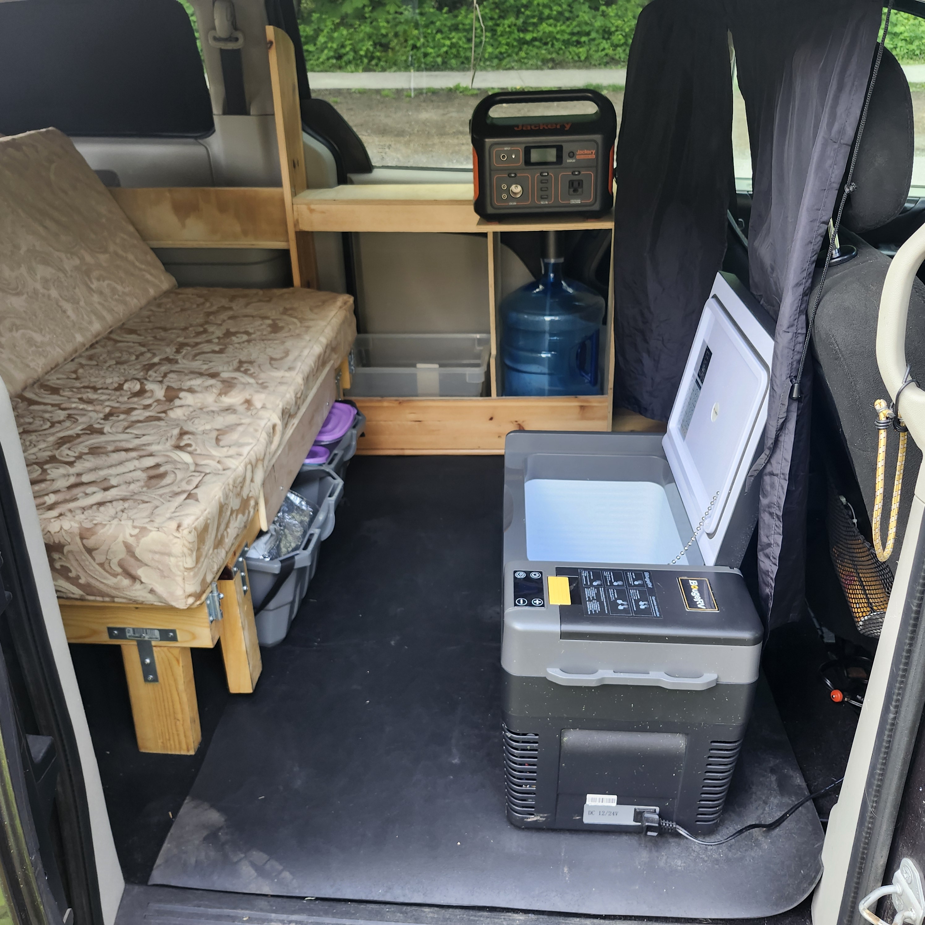 Cozy camper van interior features a bed, Jackery power, water jug, and fridge. Perfect for your next rv rental!. Chrysler Dodge Grand Caravan 2015