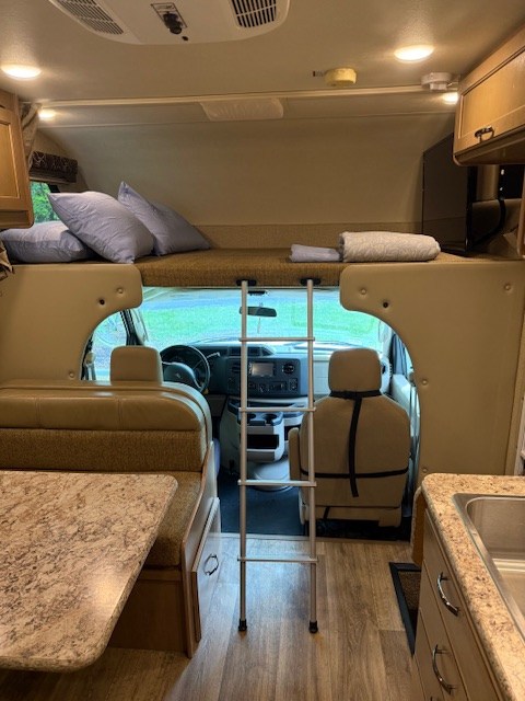 RV rental interior: A spacious motorhome featuring a cab-over bunk with ladder, dinette, and kitchen. Ready for adventures!. Thor Freedom Elite 2017