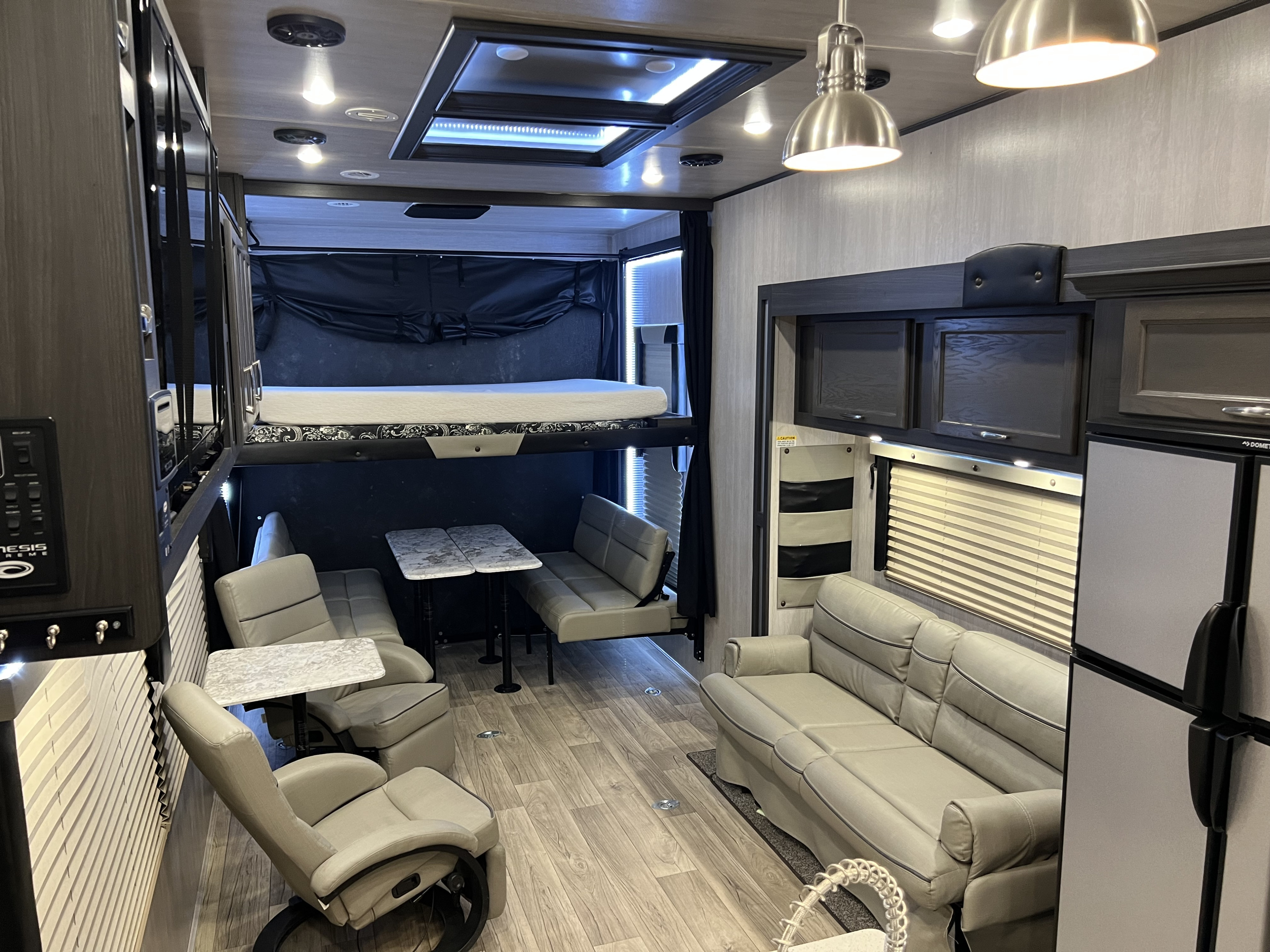 Spacious RV rental interior: a versatile living area with an upper bunk bed, sofa, dinette, and kitchen amenities.. Genesis Supreme 2023