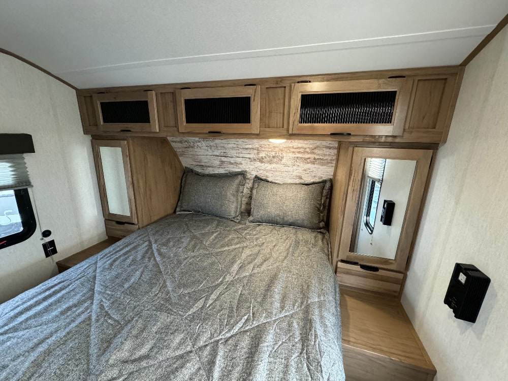 Comfortable RV rental bedroom featuring a cozy bed, overhead storage, and mirrored nightstands.. Forest River Alpha Wolf 280 QBS-L 2024