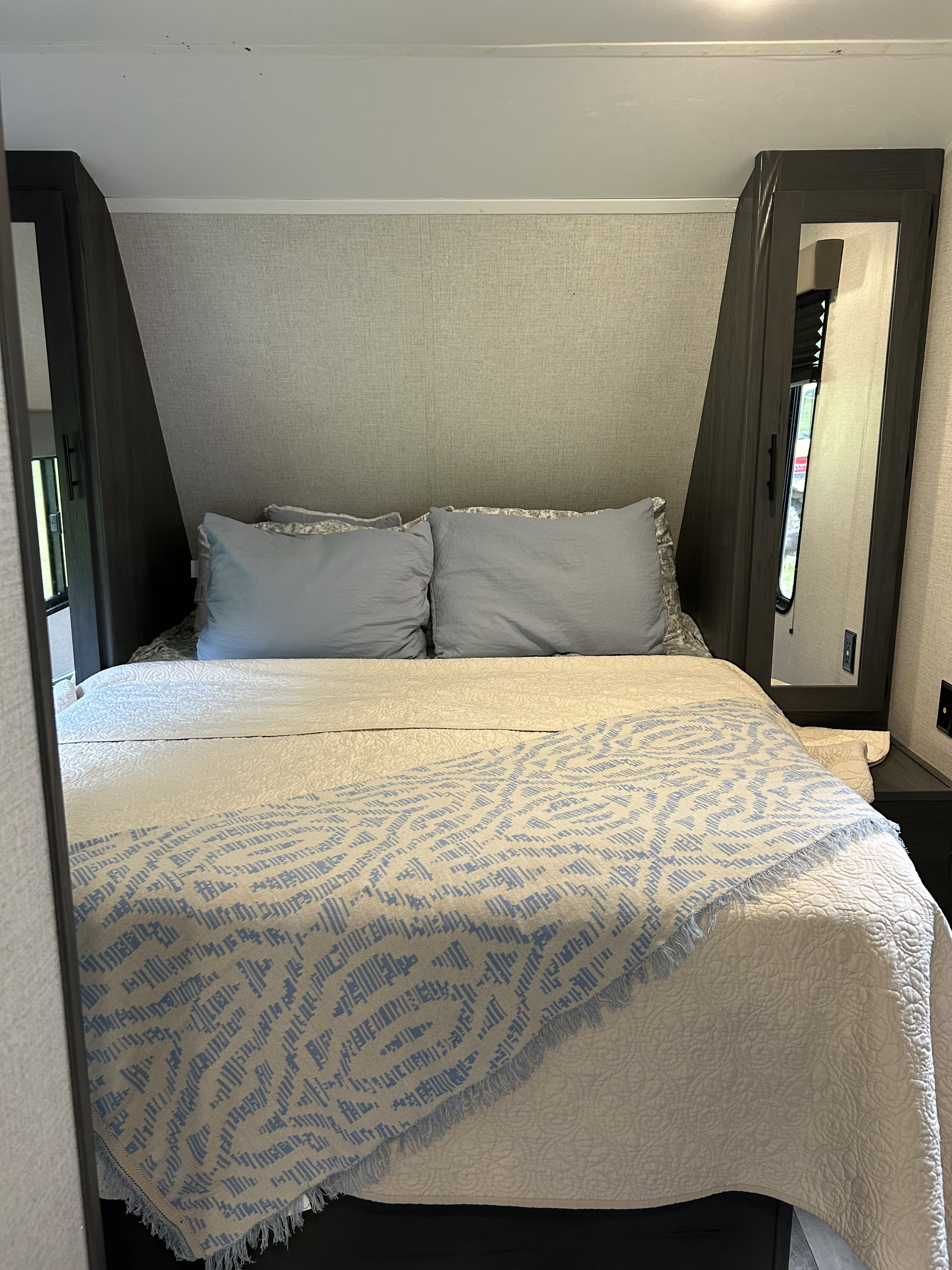 Cozy RV rental bedroom: full bed with light blue pillows, quilted comforter, and patterned throw blanket.. Aspen Trail LE 2022