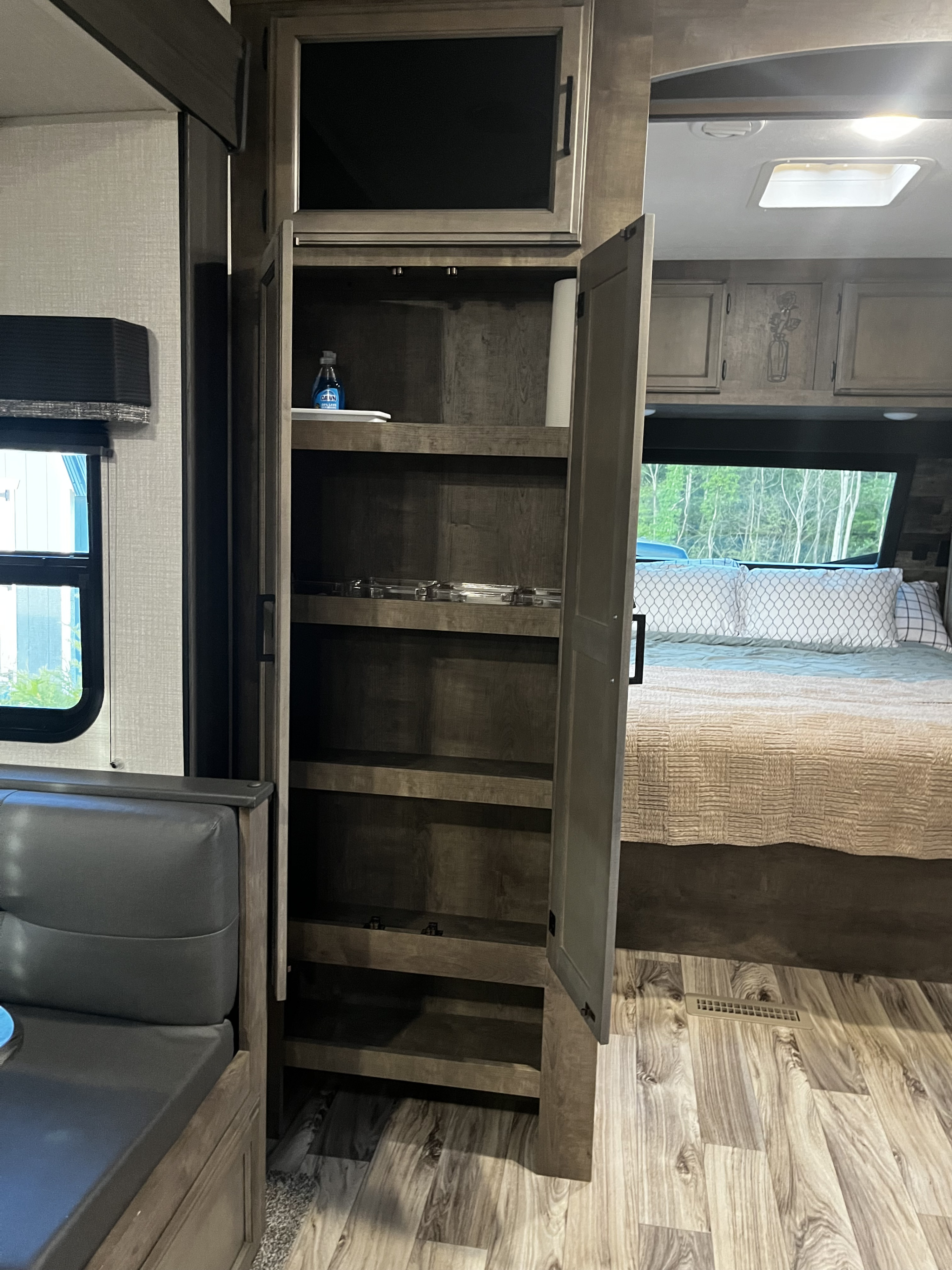 View inside an **RV rental**: a tall pantry with open shelves, a bedroom, and part of the dining area.. Venture SPORTTREK 332VBH 2021
