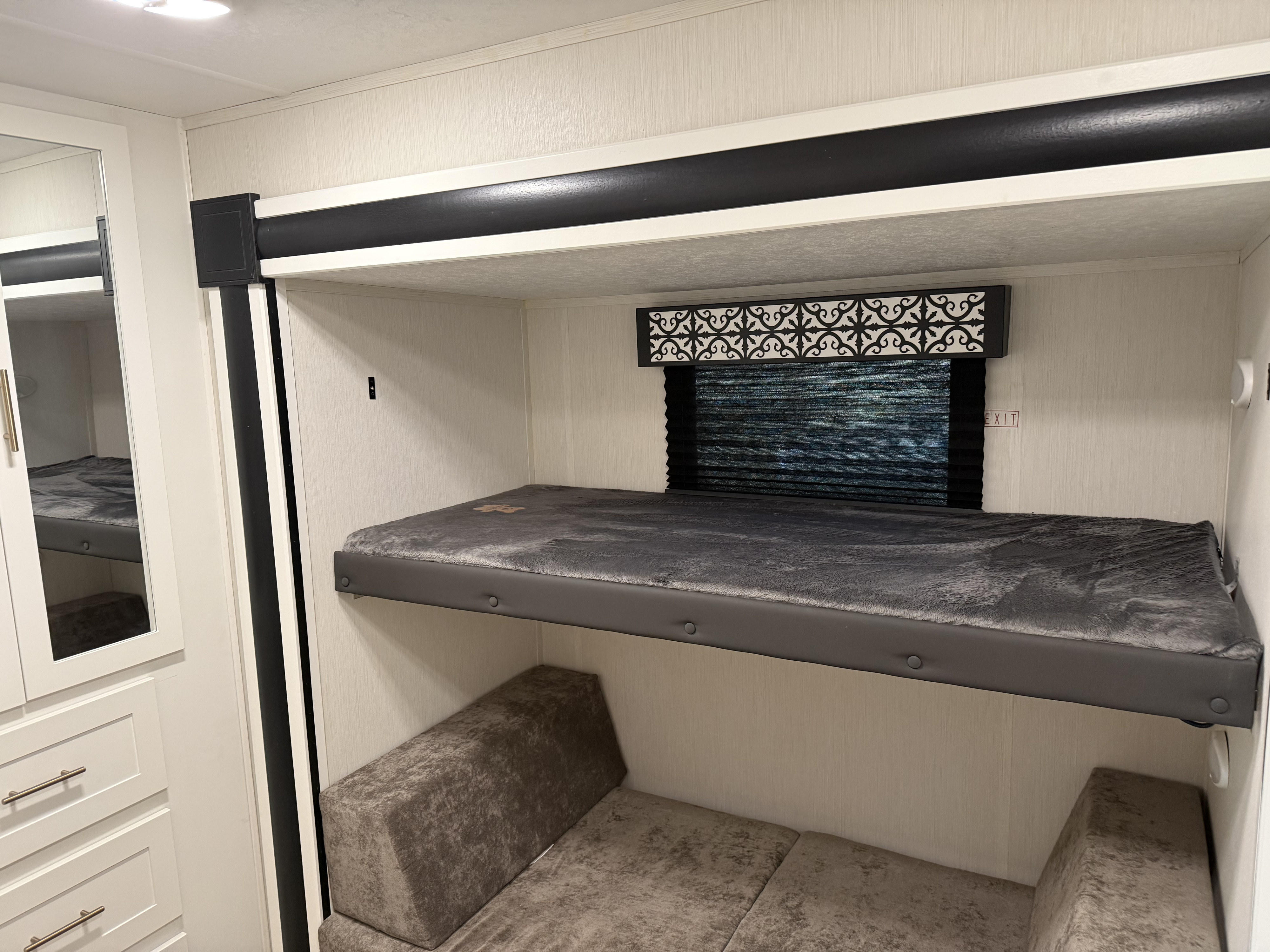RV rental bunk beds: upper with grey blanket, lower seating converts to bed. Bright, modern interior for family travel.. Forest River Wildcat 2021