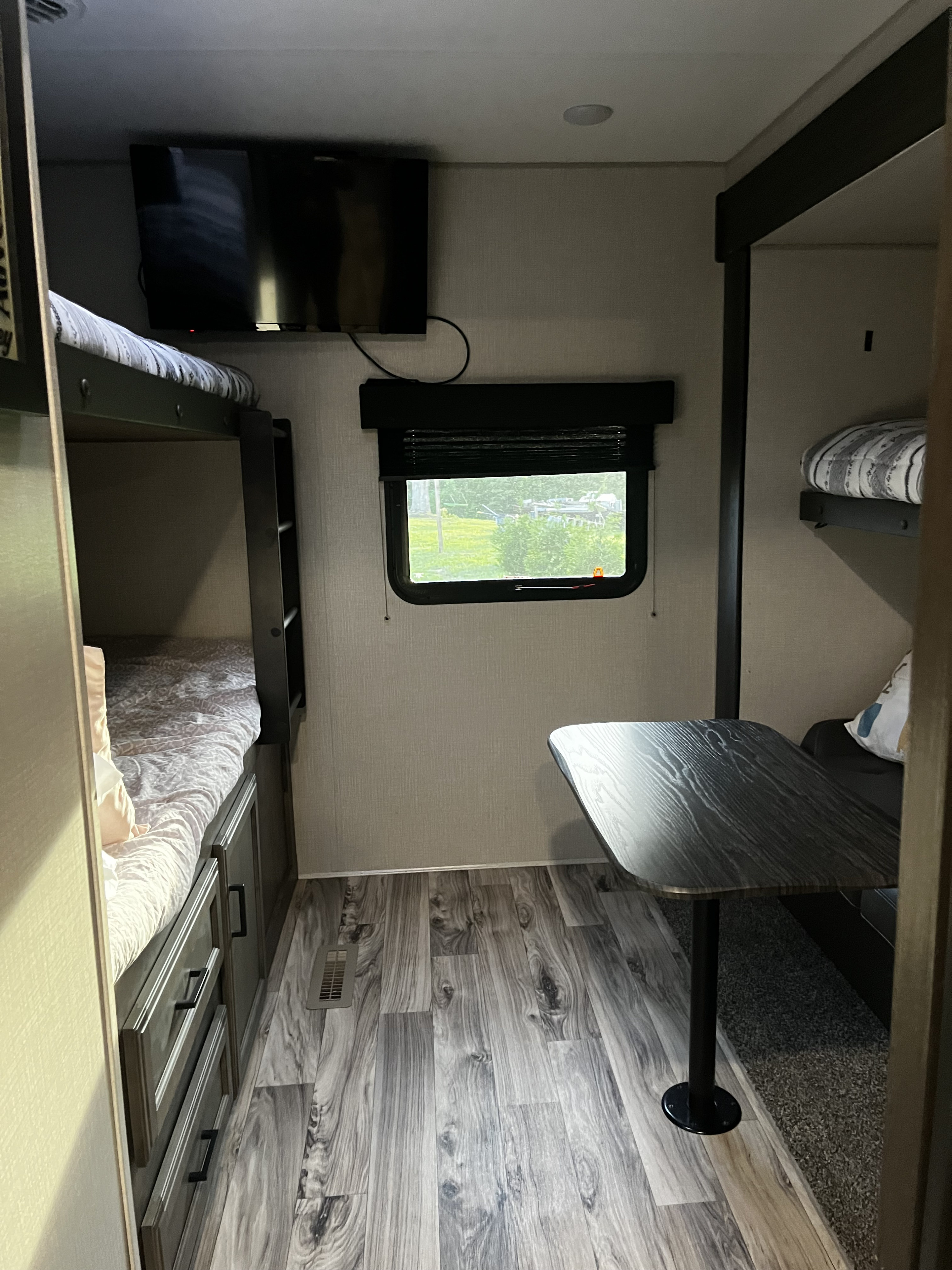 Cozy RV rental interior featuring bunk beds with storage, a dining table, and a window with green views.. Venture SPORTTREK 332VBH 2021