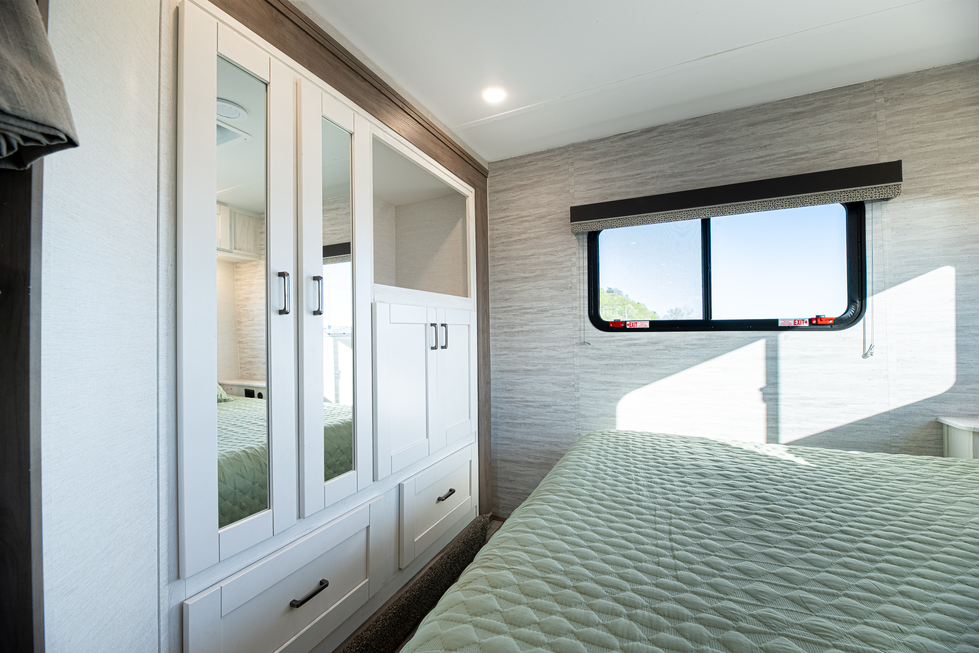 Spacious RV rental bedroom featuring a mirrored wardrobe, comfortable bed, and a large window, providing ample storage and natural light.. Gulf Stream Conquest 2024