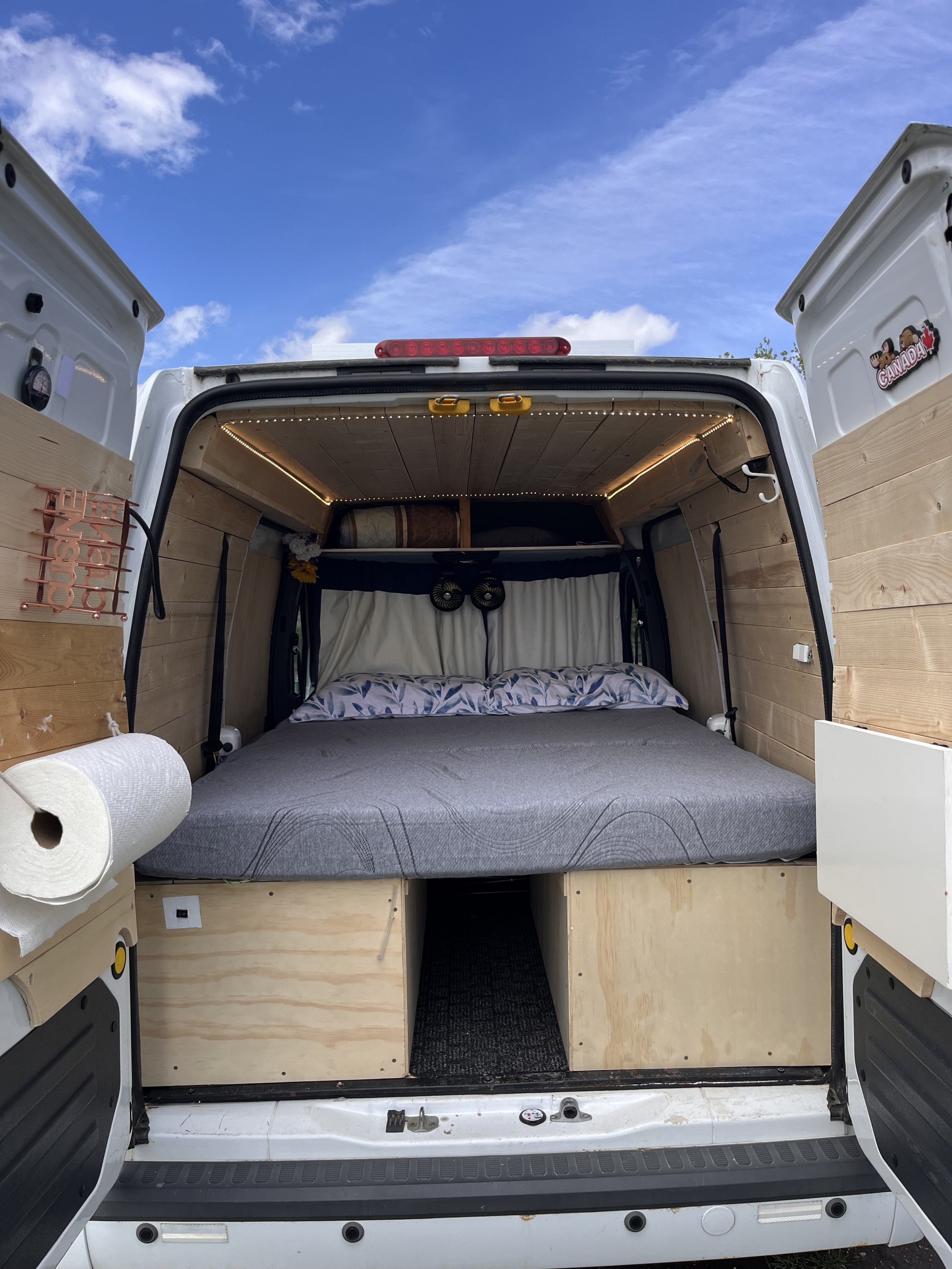 Inside this RV rental: a modern camper van conversion with a comfortable bed, wooden walls, LED lighting, and storage.. Ford Transit custom 2011