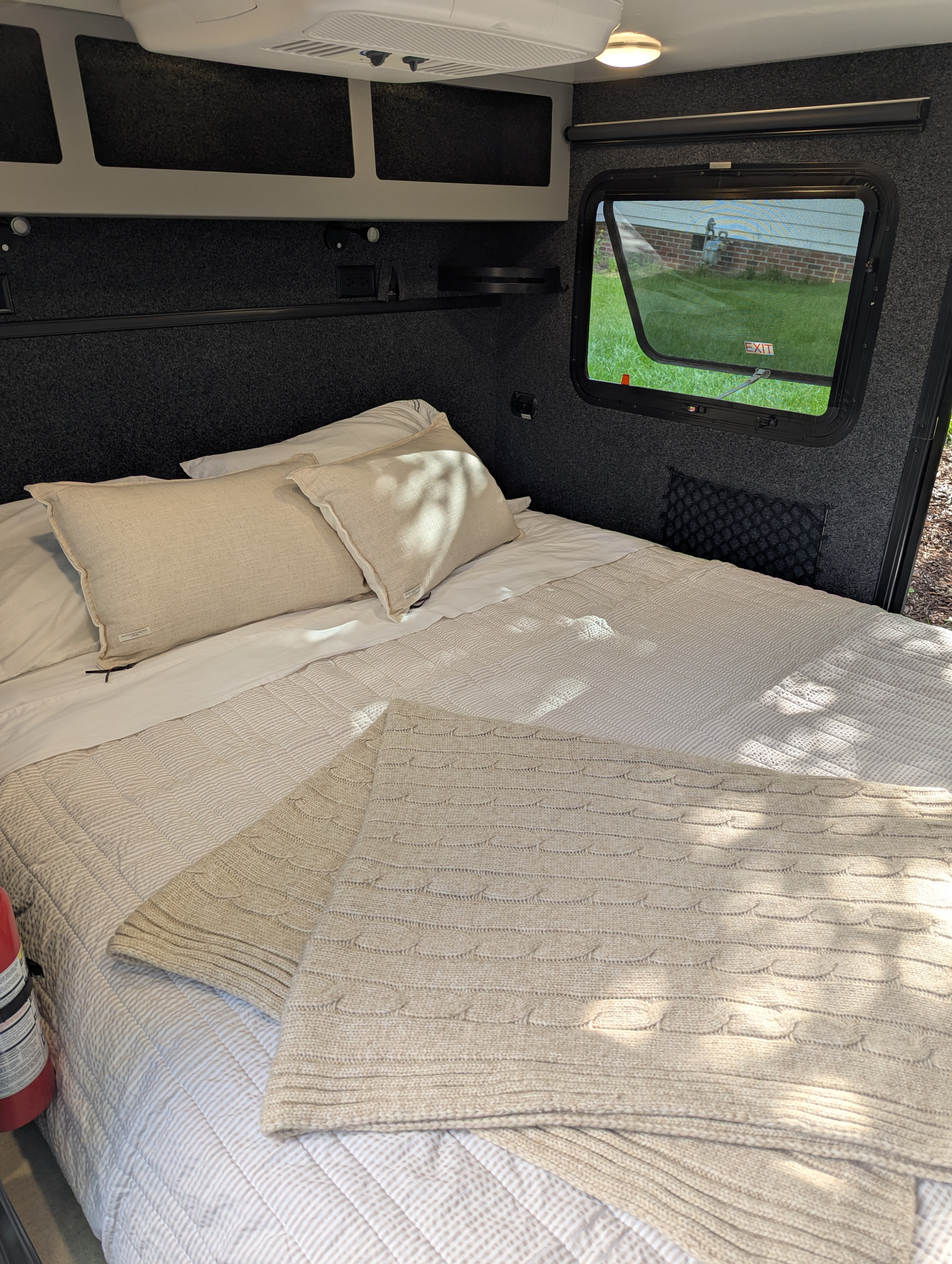 Cozy RV rental bedroom featuring a comfortable bed with light bedding and overhead storage, perfect for your travel adventures.. Encore RV ROG 2022