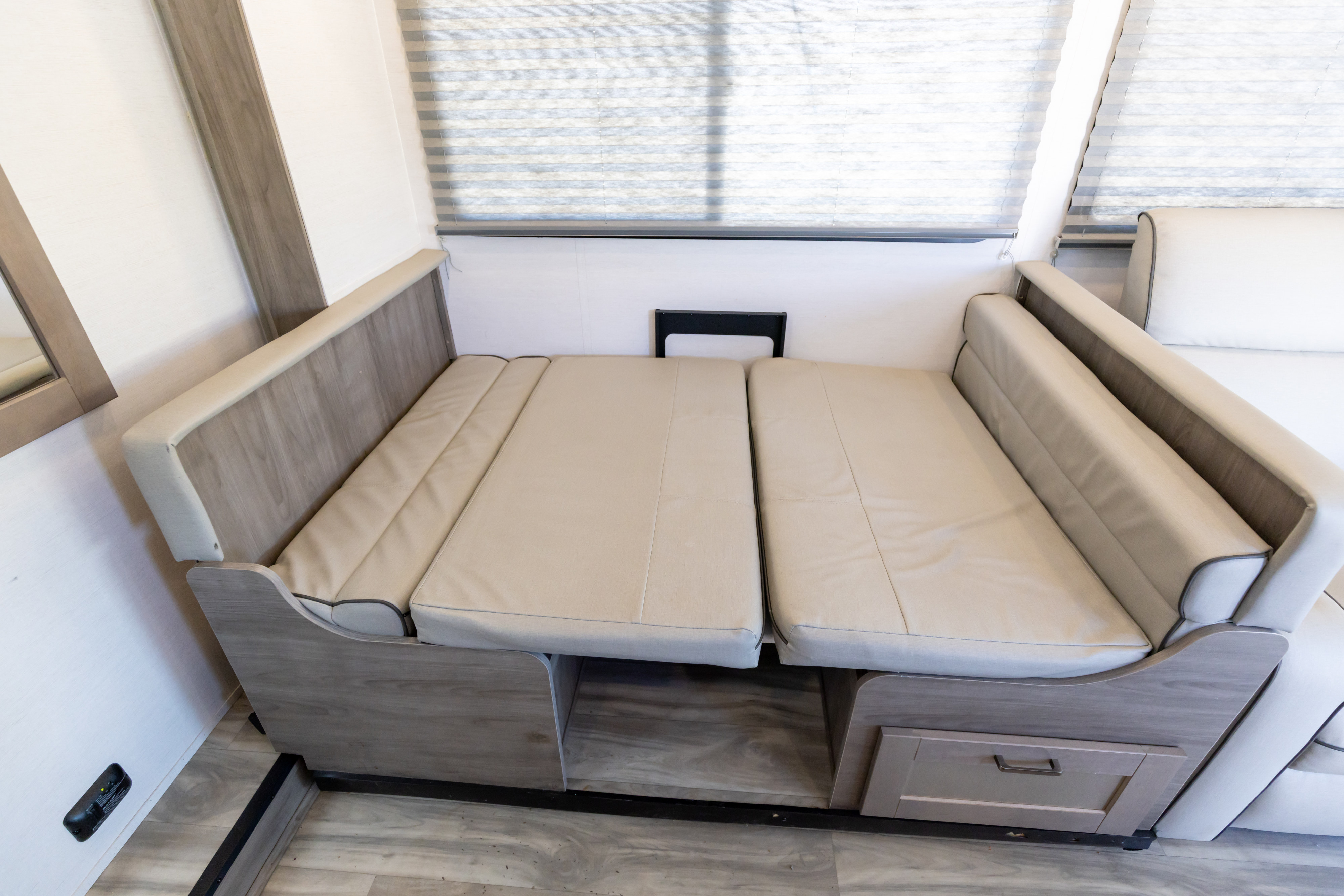 RV rental interior: a versatile dinette with beige cushions folded flat, forming a sleeping area atop a wood base.. Gulf Stream Conquest 2024
