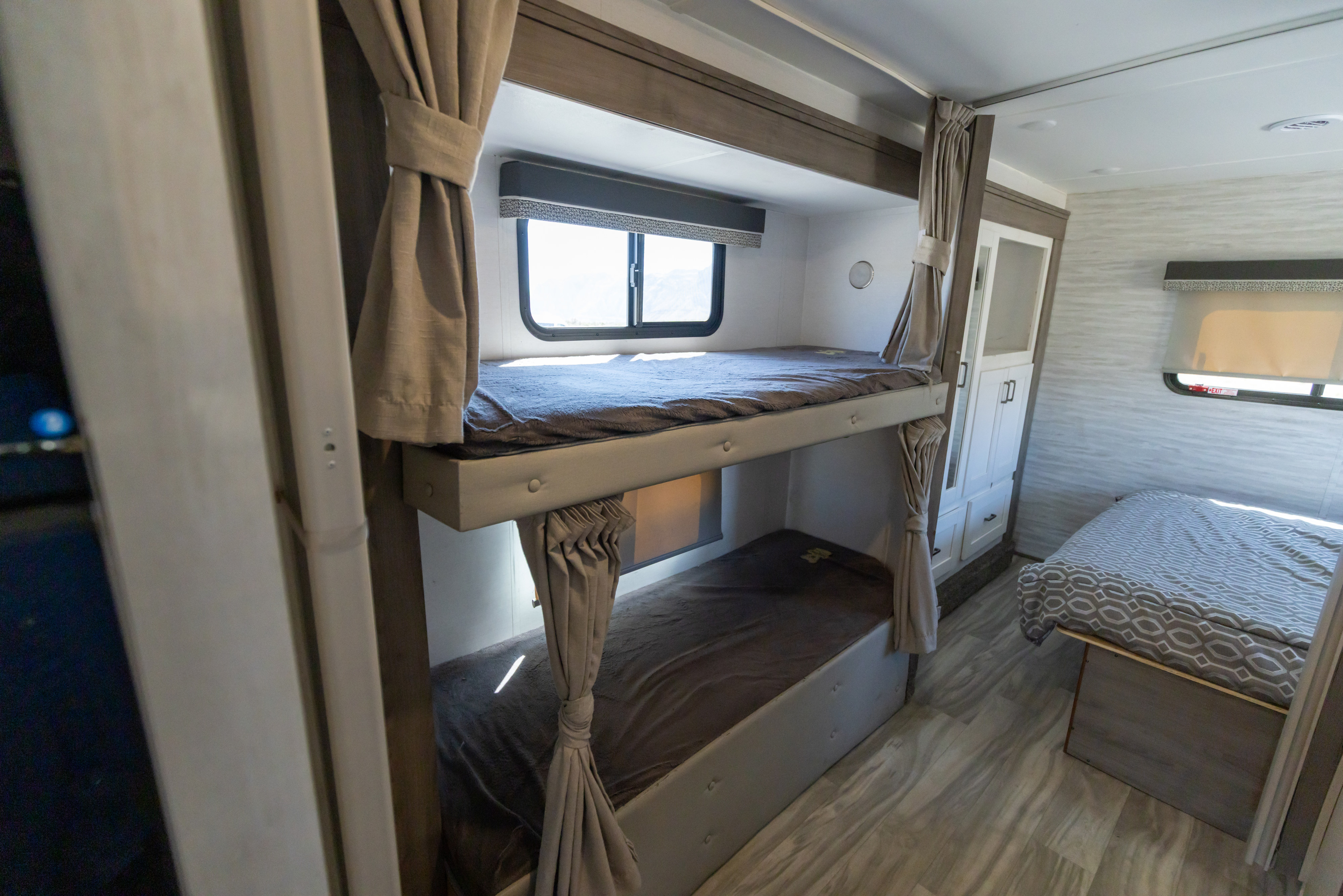 RV rental interior showing bunk beds with privacy curtains and a main bed, providing comfortable sleeping for travelers.. Gulf Stream Conquest 2024