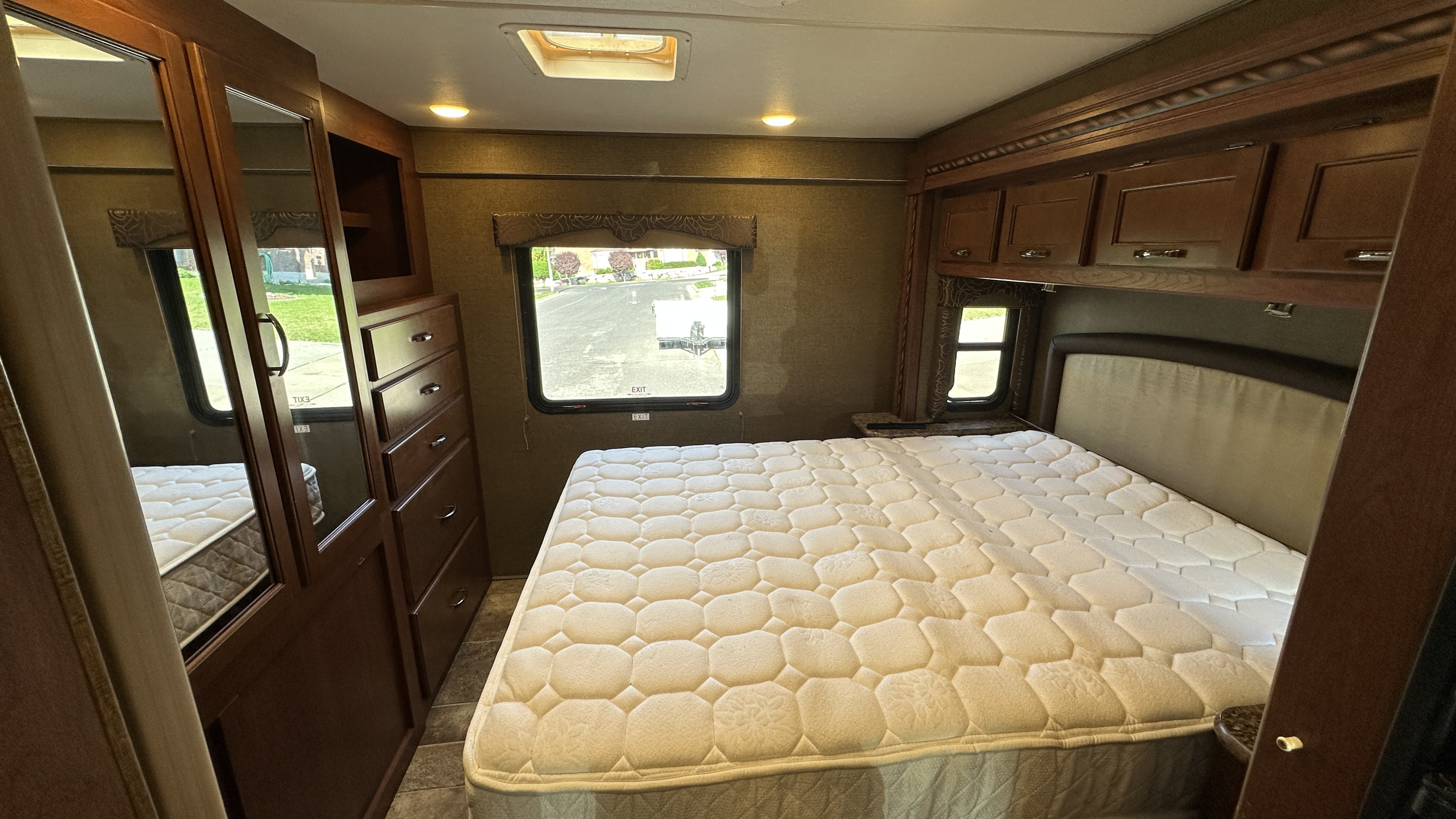 Spacious RV rental bedroom with a comfortable bed, mirrored wardrobe, and overhead storage. Ideal for travel.. Thor Freedom Elite 2016