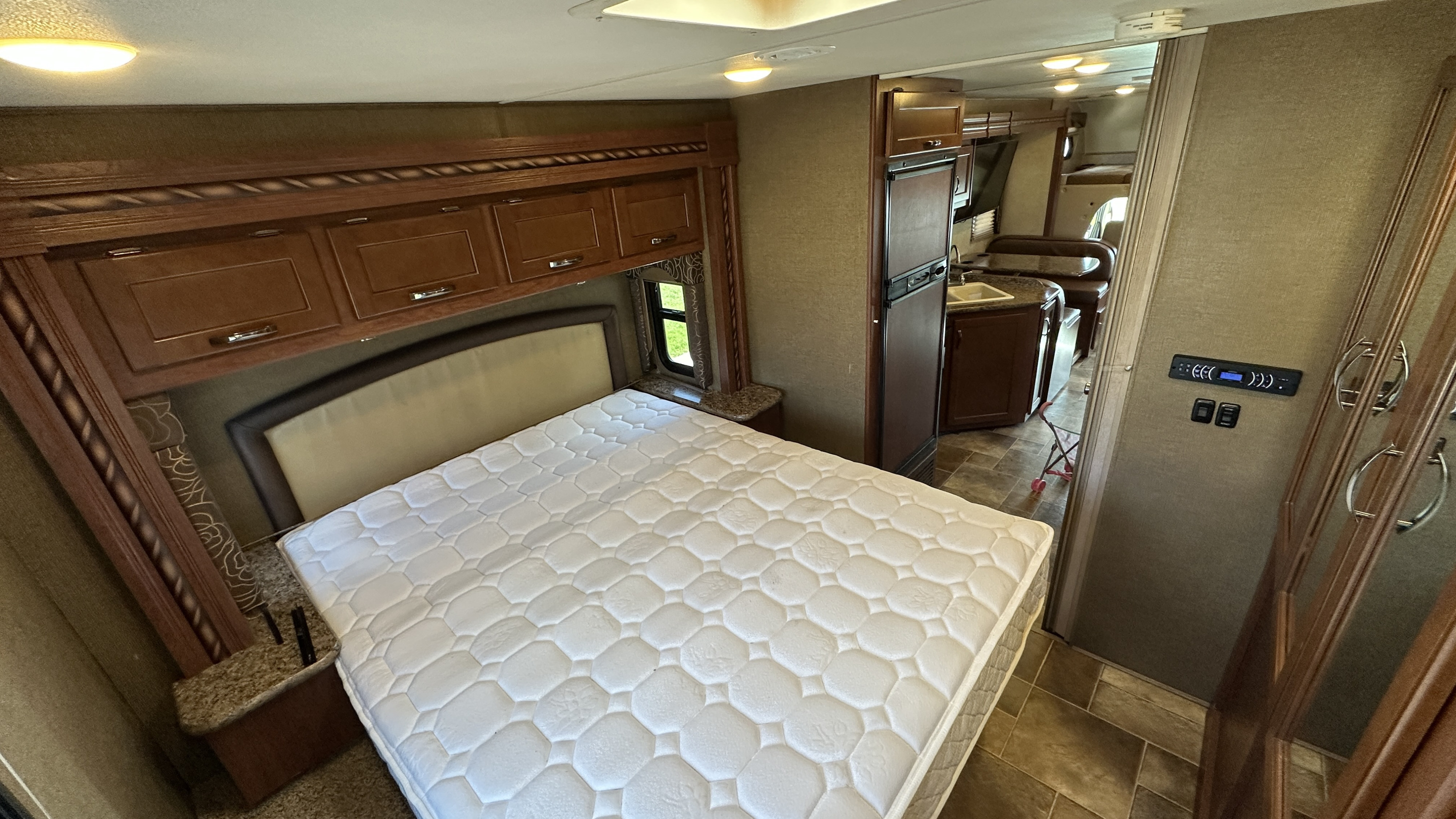 Step into this inviting RV rental: a clean bedroom with a large white mattress, linked to a functional kitchen and dining area.. Thor Freedom Elite 2016