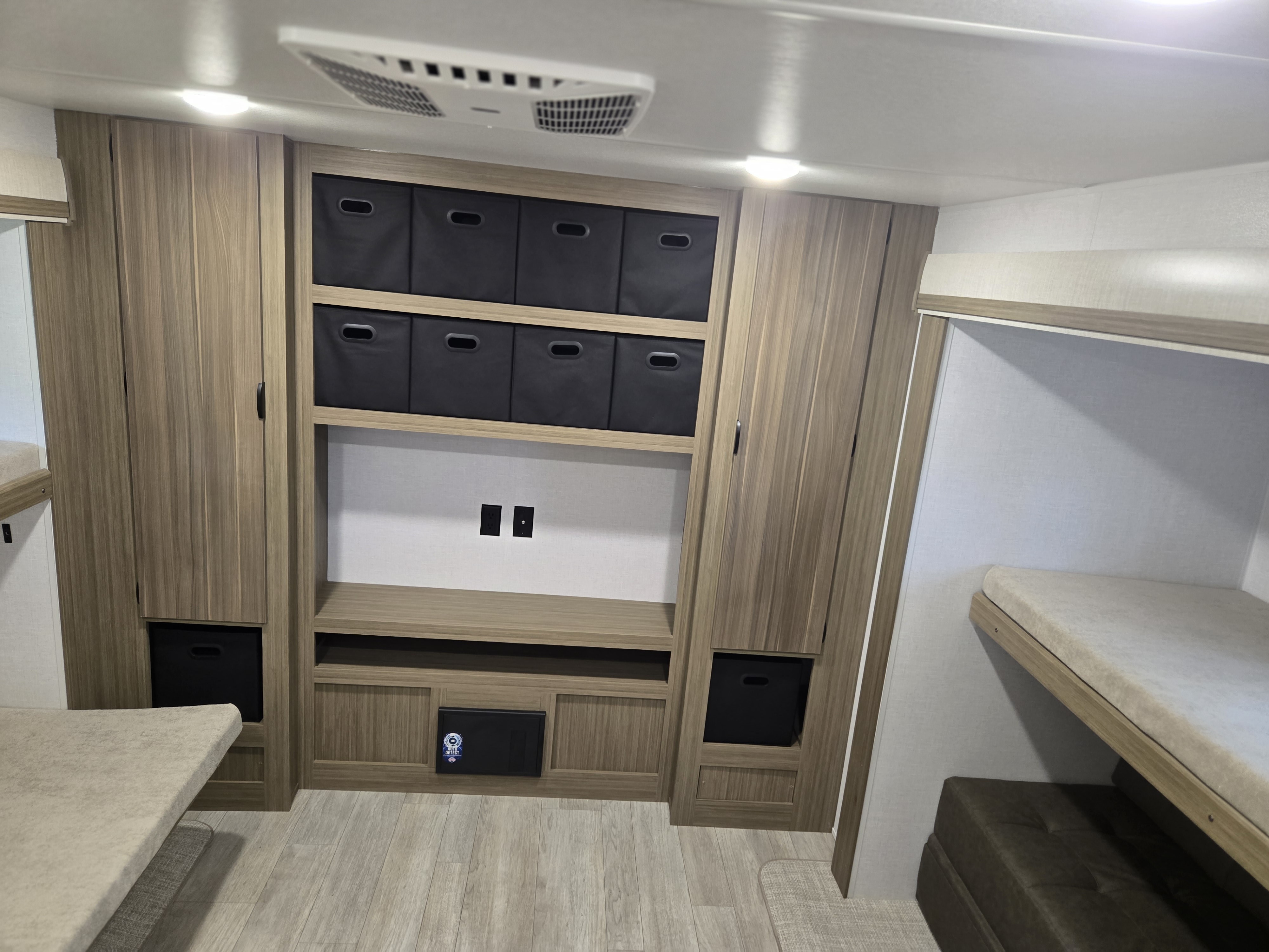 This RV rental interior features versatile wooden storage cabinetry with black bins, power outlets, and comfortable bunk beds.. Wildwood 31KQBTS 2025