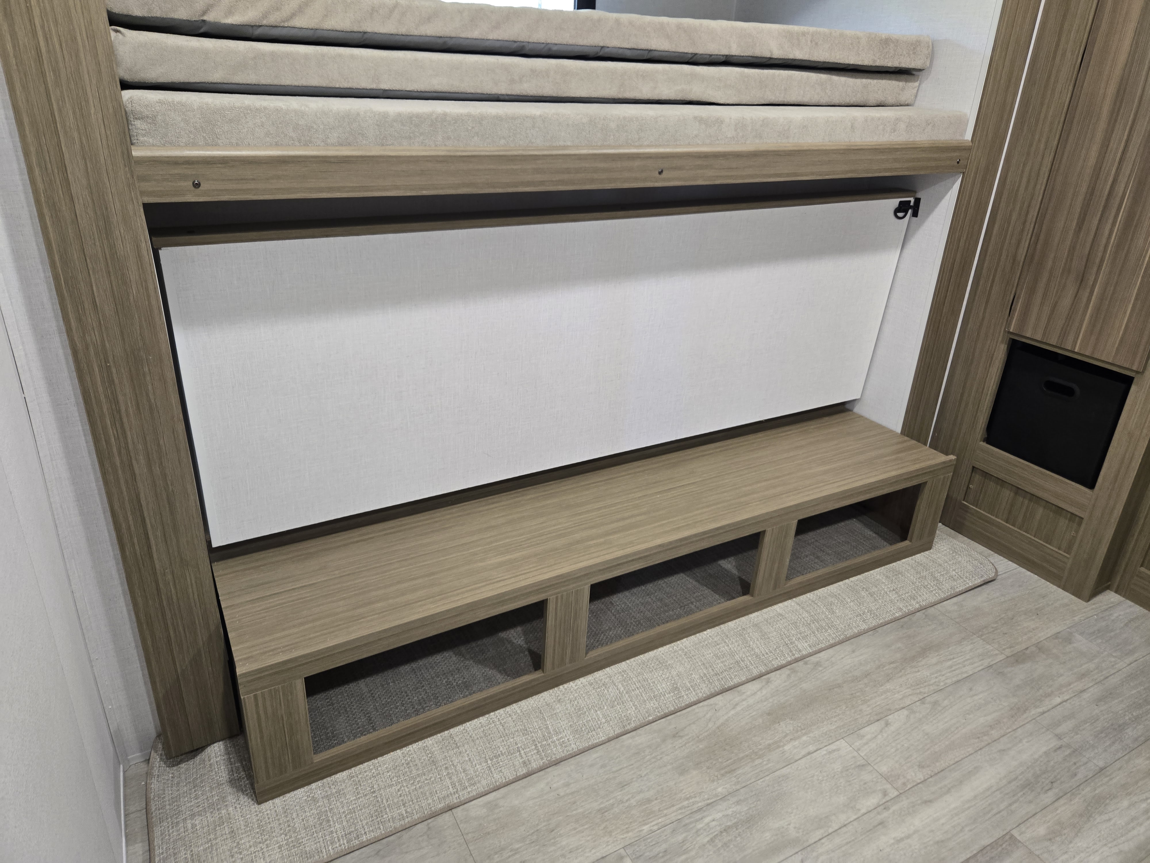 This RV rental features a compact, light wood interior with convertible lower bunk bed seating and integrated storage.. Wildwood 31KQBTS 2025