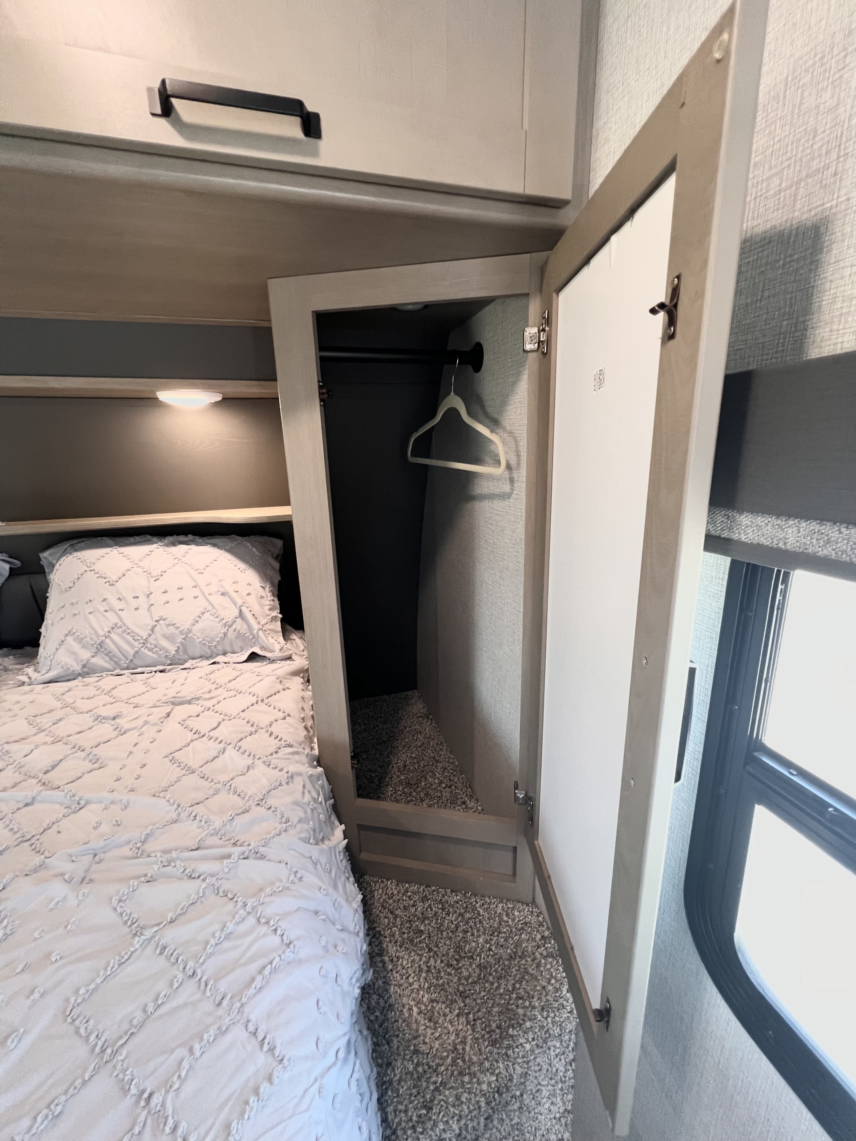 Cozy RV rental bedroom with a comfortable bed, mirrored closet door, and overhead storage. Ideal for a relaxing journey.. Grand Design Reflection 2024