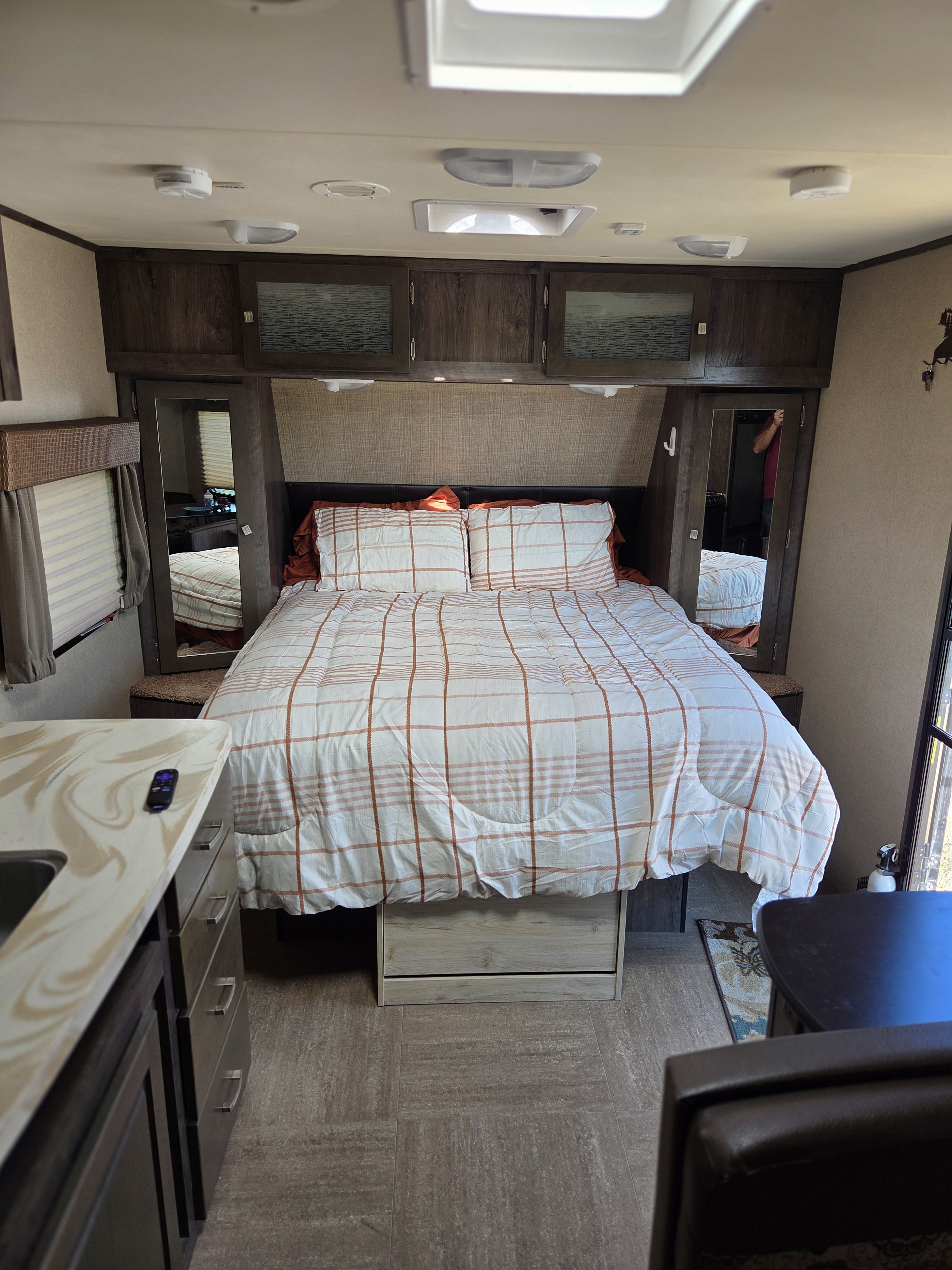 RV rental camper interior: a cozy bedroom with plaid bedding, mirrored closets, and a kitchenette counter.. Dutchmen Kodiak 2014