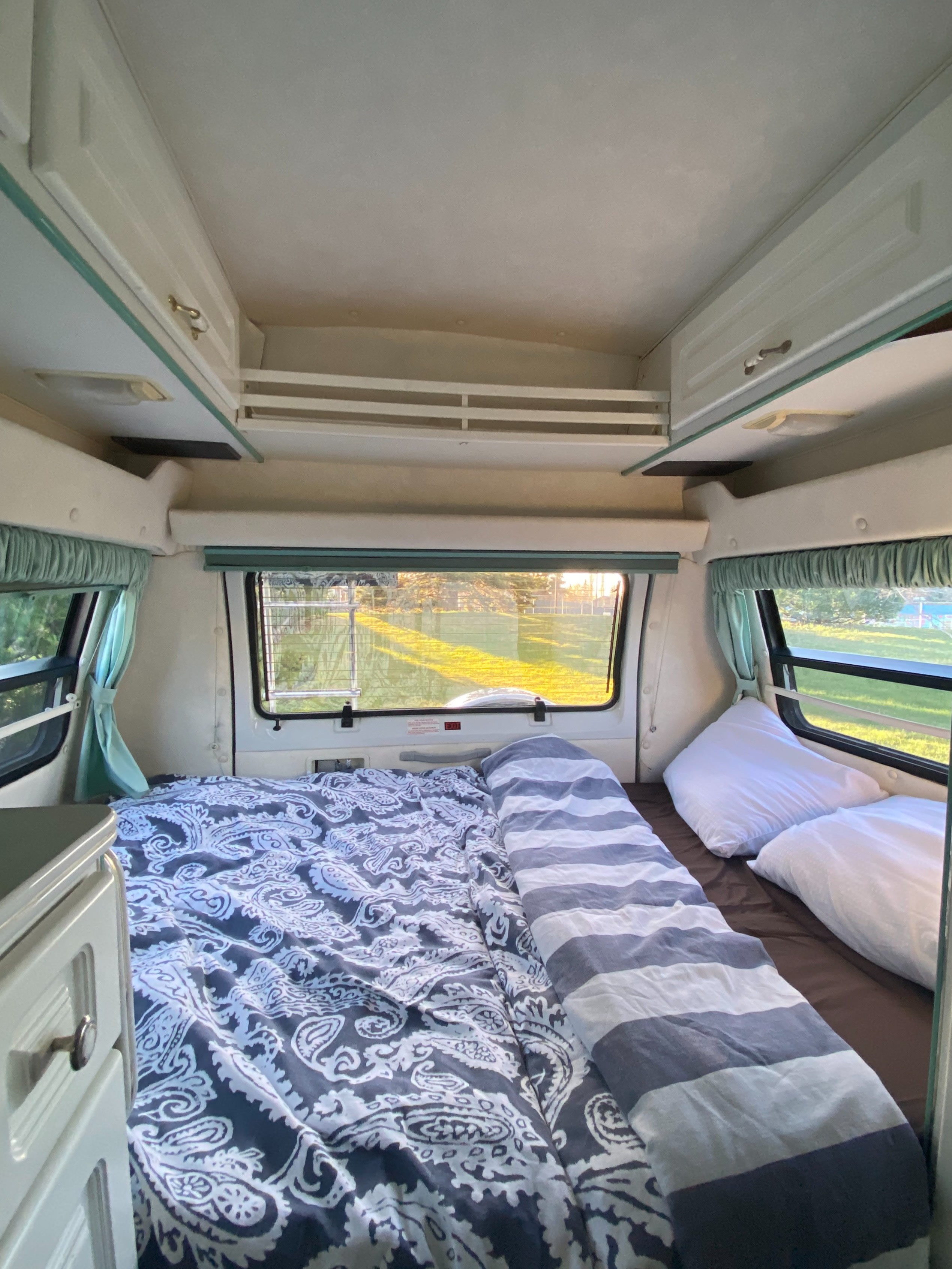 Experience comfortable travel in this RV rental's bedroom, complete with a cozy bed, ample storage, and scenic window views.. Leisure Travel Freedom 1994