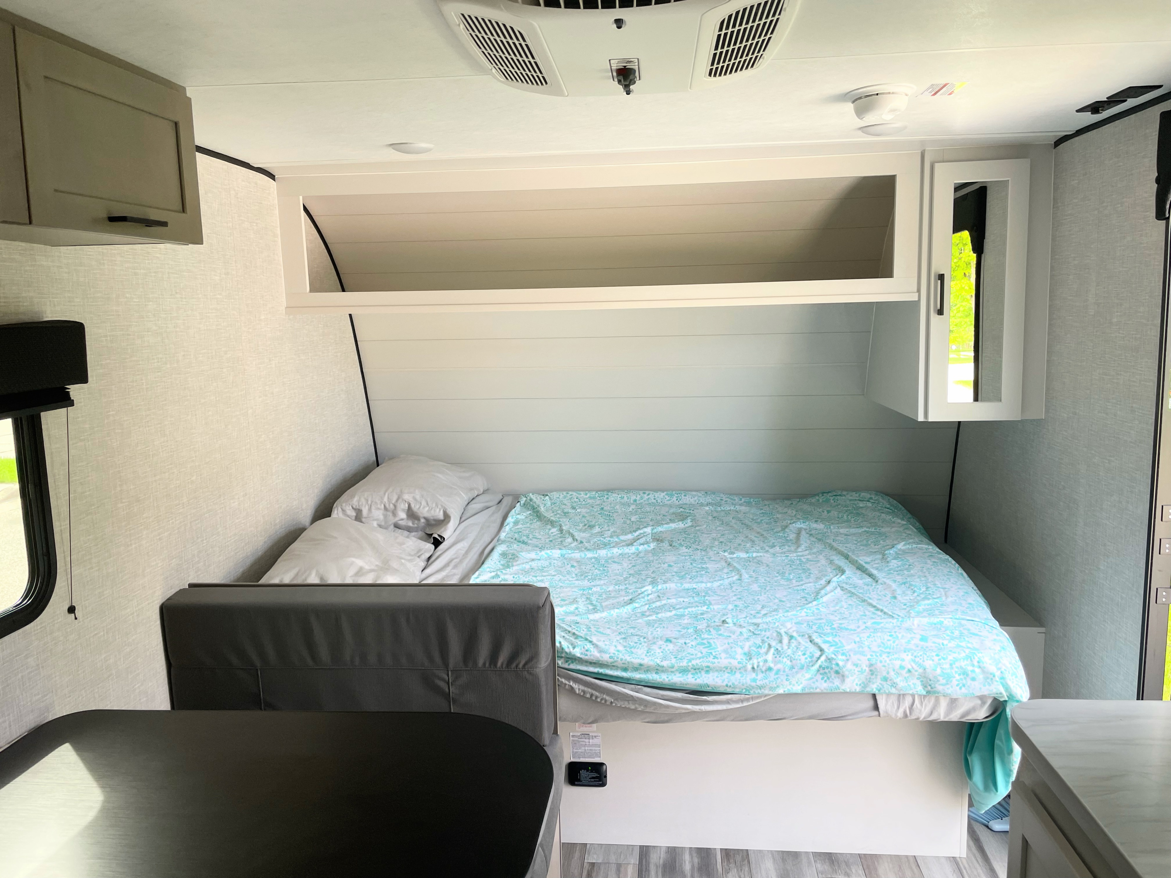 Cozy RV rental interior featuring a comfortable bed, overhead storage, and a partial dinette, ideal for travel.. Jayco Jay Feather Air Super Lite 17BHSL 2025