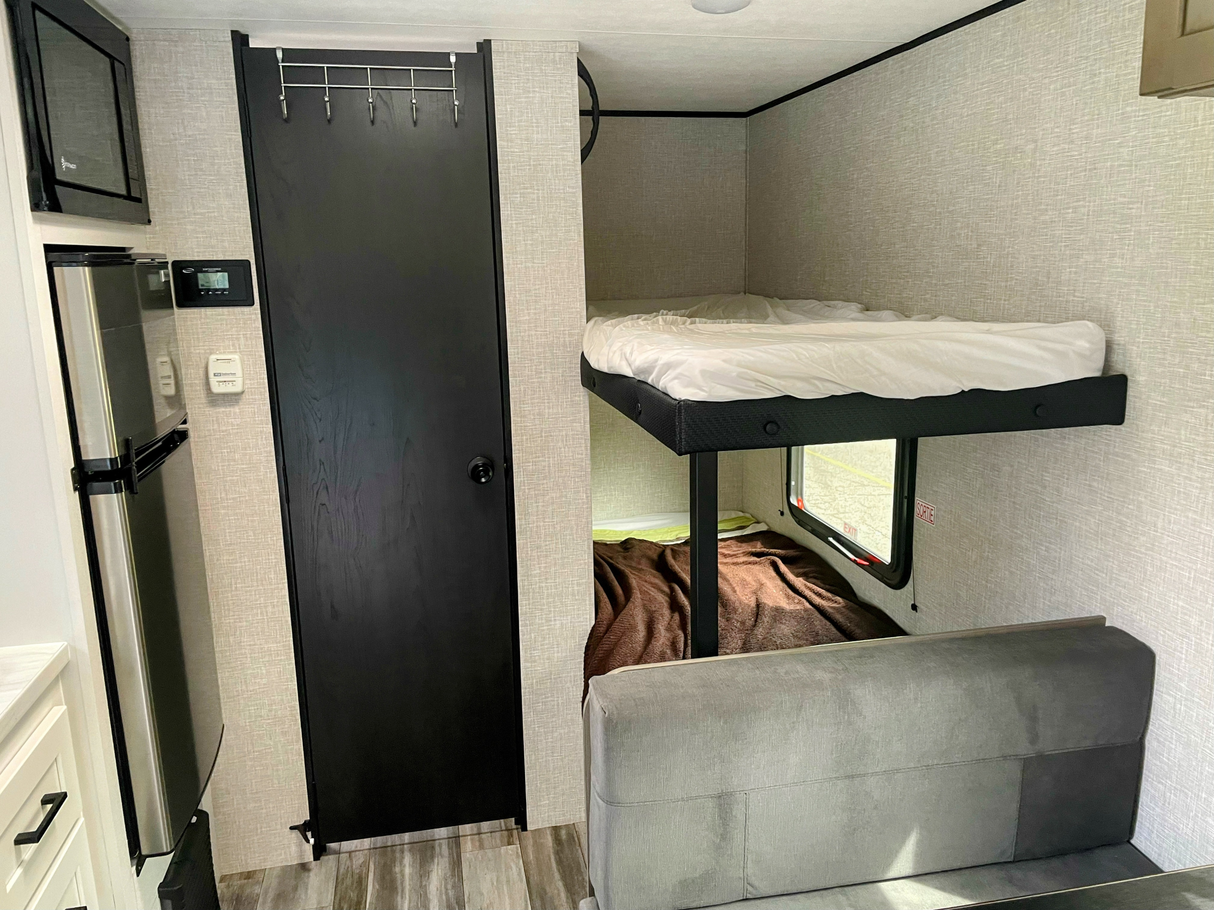 Inside this RV rental: Bunk beds, mini-fridge, microwave, and a comfy couch, perfect for compact living on the go.. Jayco Jay Feather Air Super Lite 17BHSL 2025