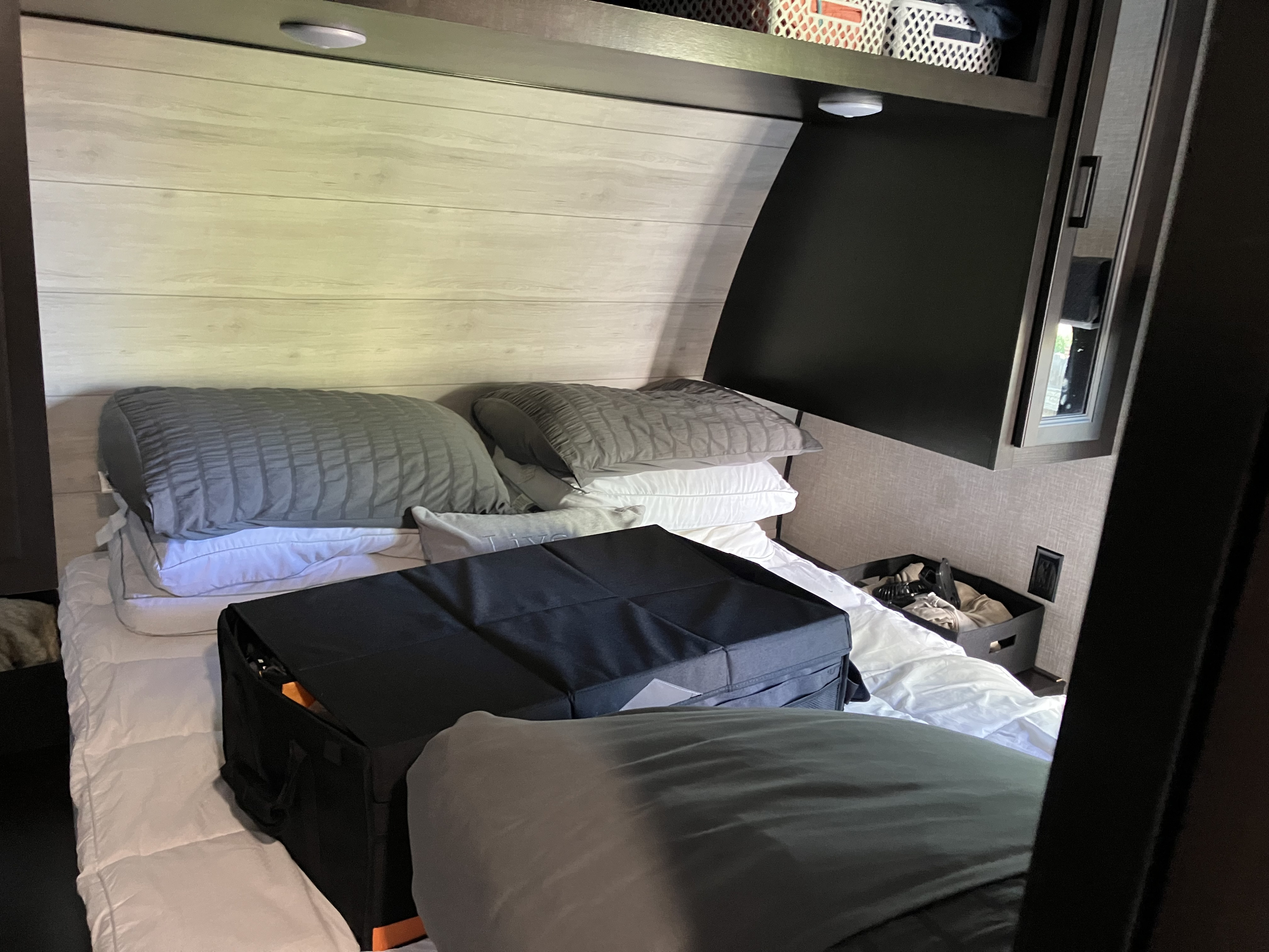 Cozy RV rental bedroom featuring a bed with grey and white pillows and a black storage organizer.. Jayco Jay Flight 2023
