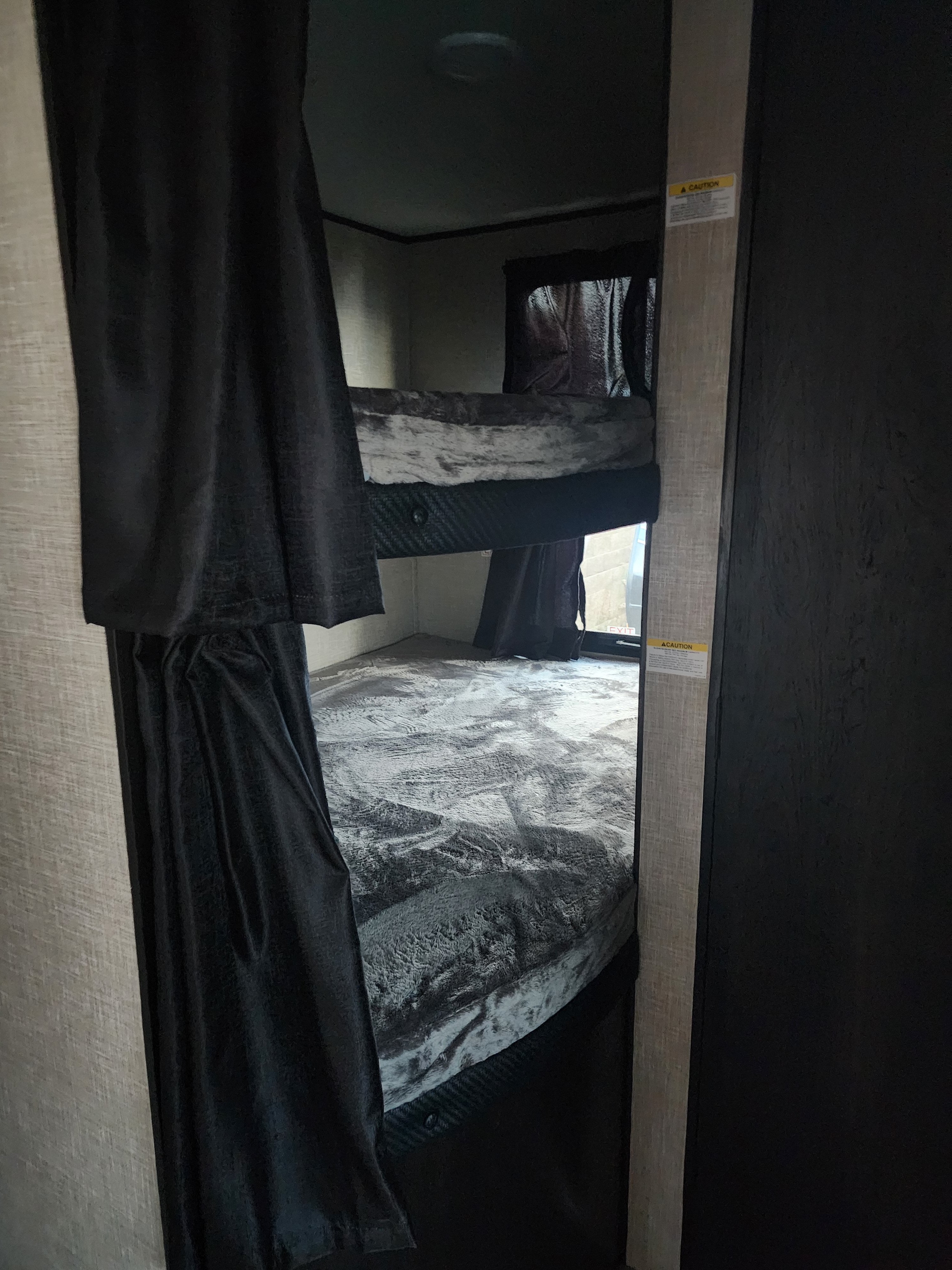 RV rental bunk beds feature dark privacy curtains & soft gray blankets, providing cozy sleeping space.. Jayco Jay Flight 2023
