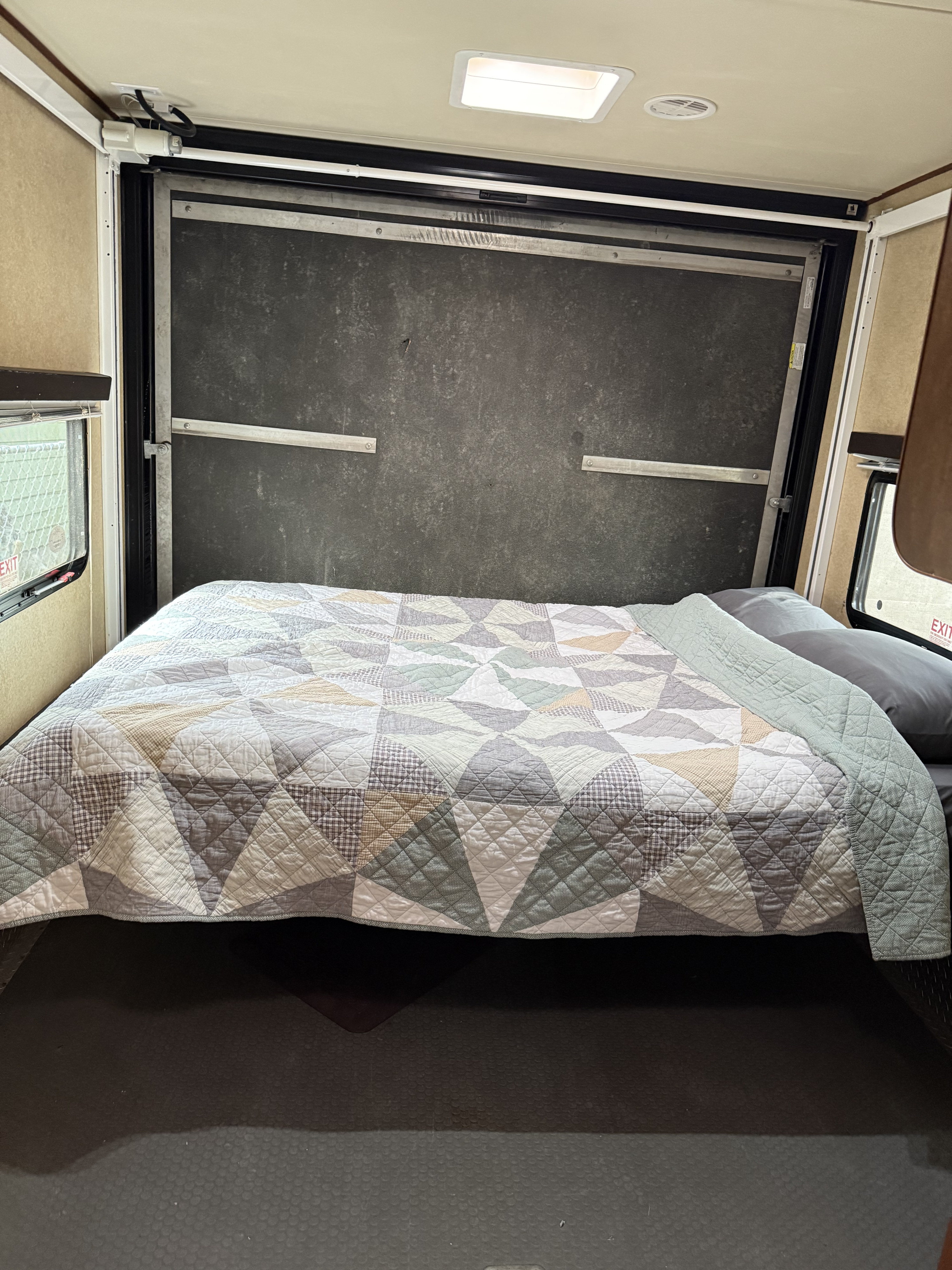 Spacious RV rental interior featuring a comfortable bed with a patterned quilt. This toy hauler offers ample sleeping space.. Forest River M-27HFS 2013