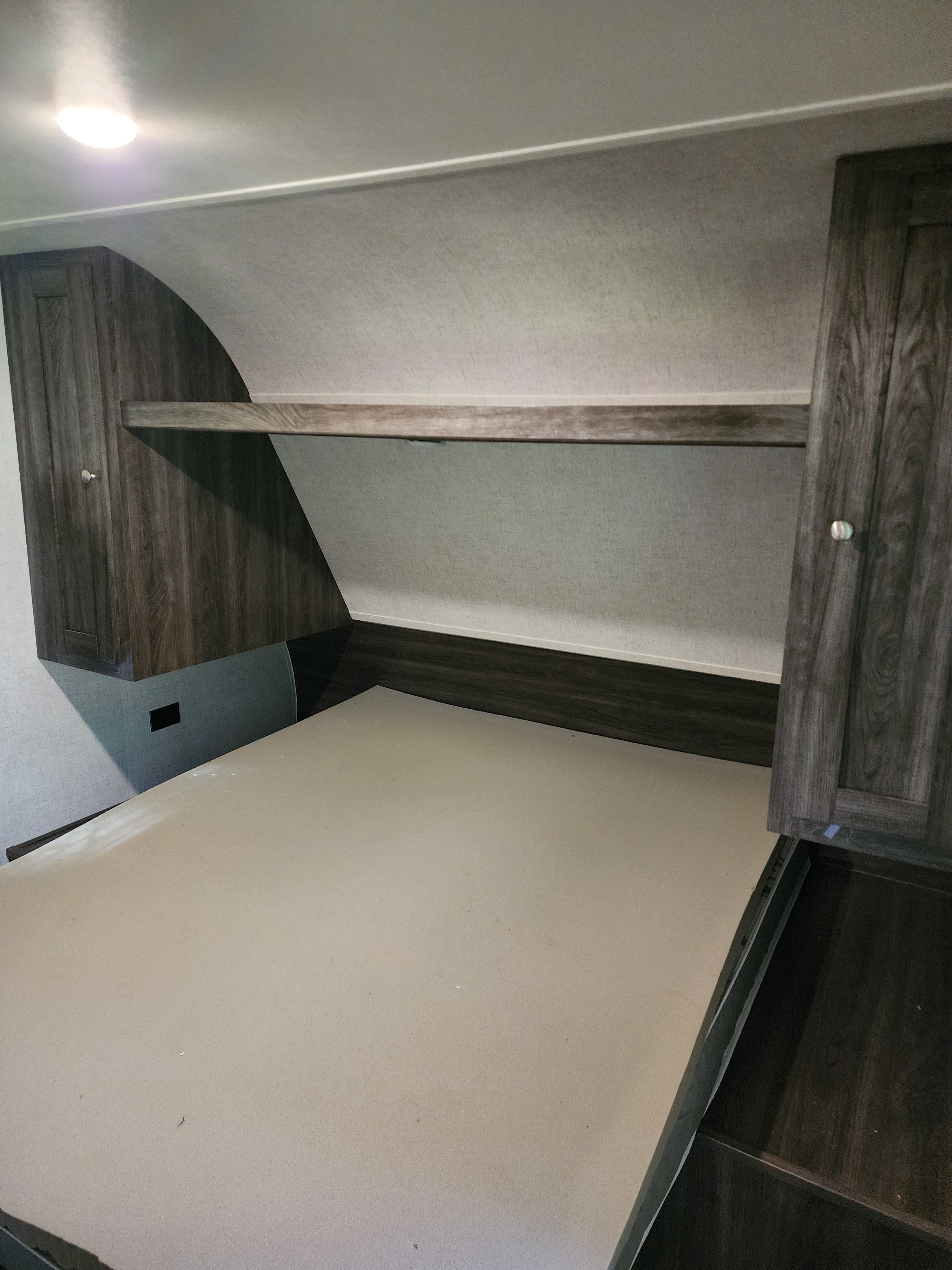This RV rental offers a compact bedroom with built-in overhead storage, a practical shelf, and a bare bed platform.. Starcraft Autumn Ridge 2020