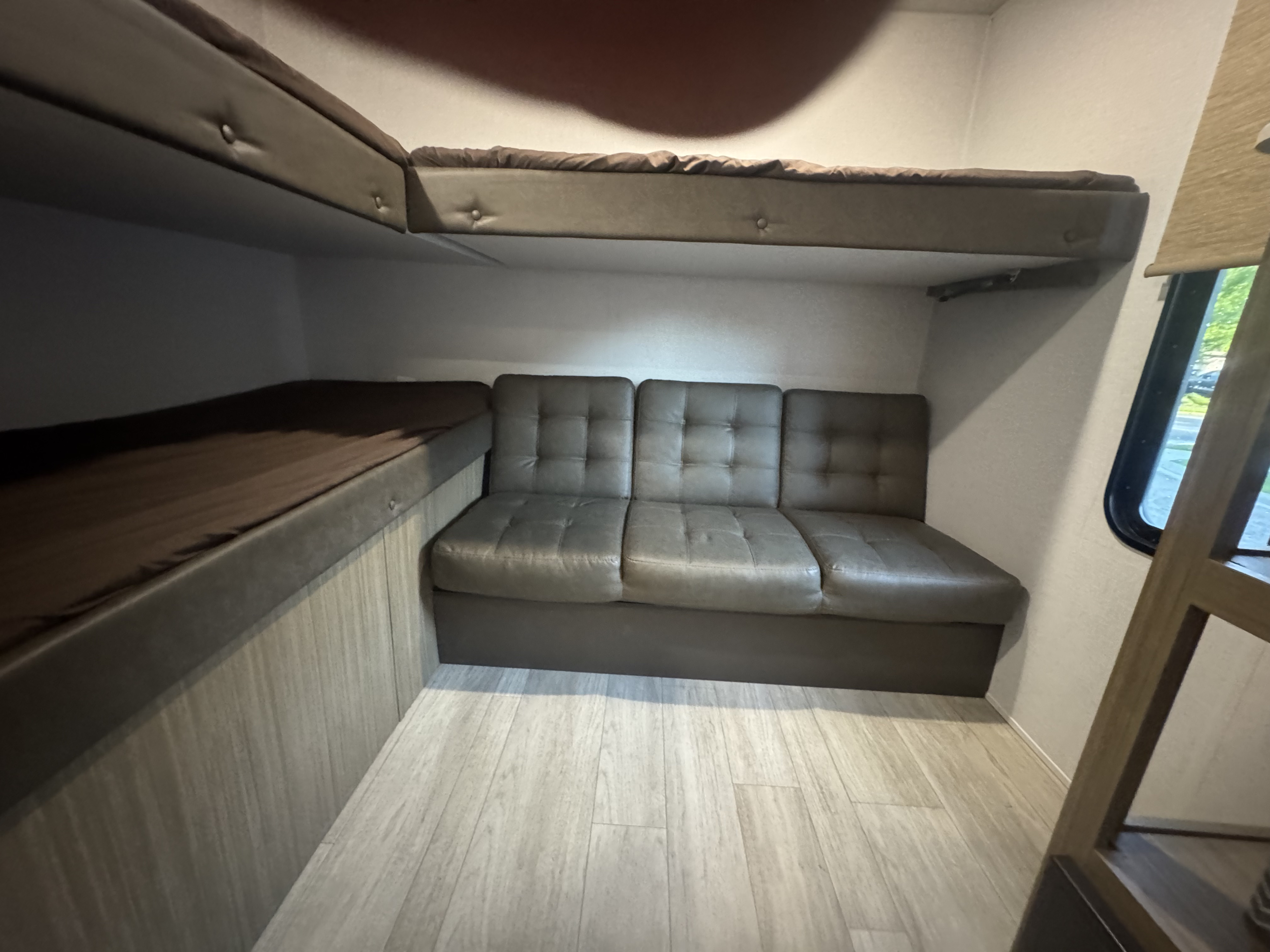 Spacious RV rental interior featuring a lower bunk bed, an upper bunk, and a modern grey sofa for comfortable trips.. Forest River Cruise Lite 2025