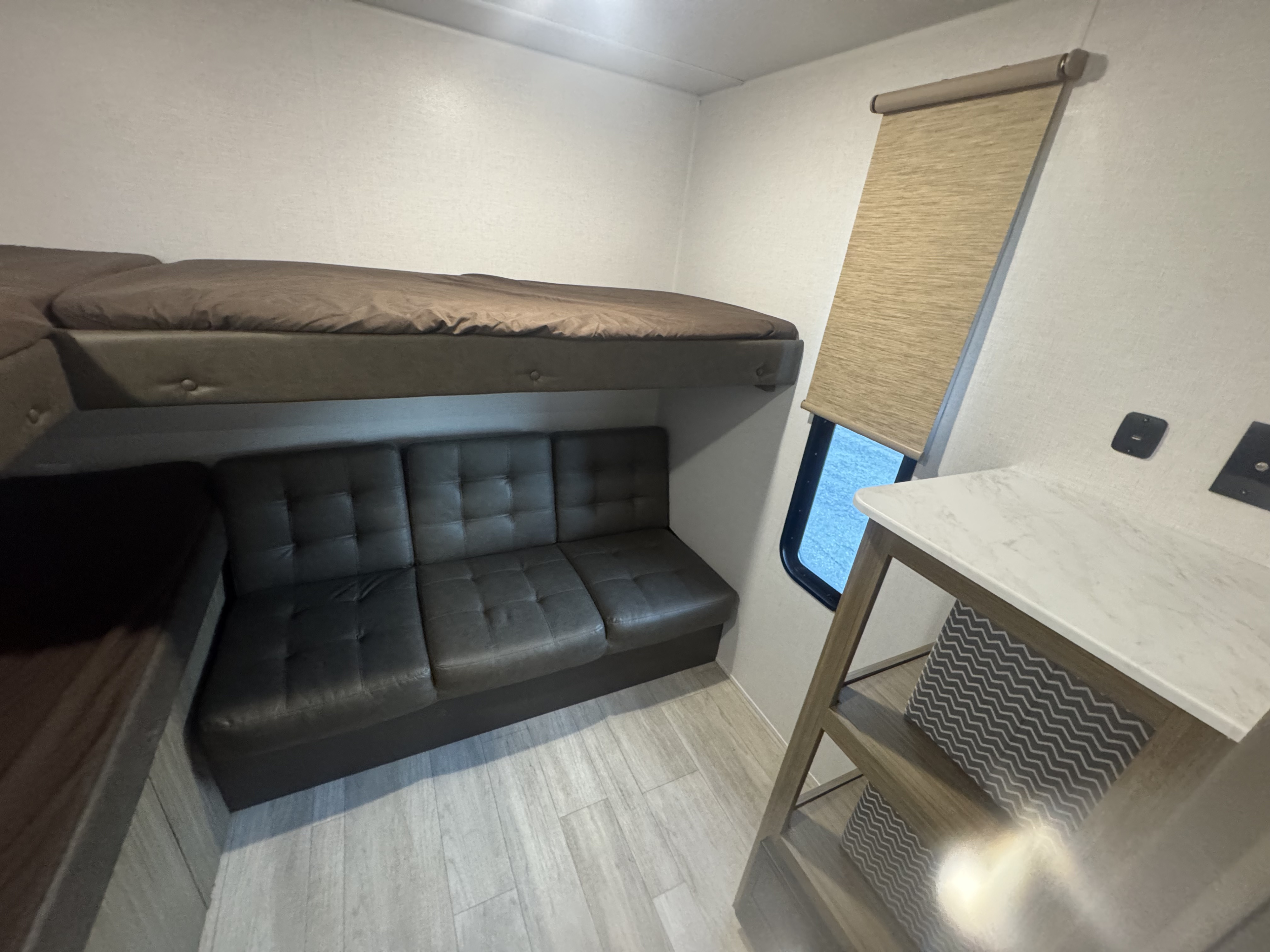RV rental interior with a bunk bed, versatile sofa seating, and a compact table by the window.. Forest River Cruise Lite 2025
